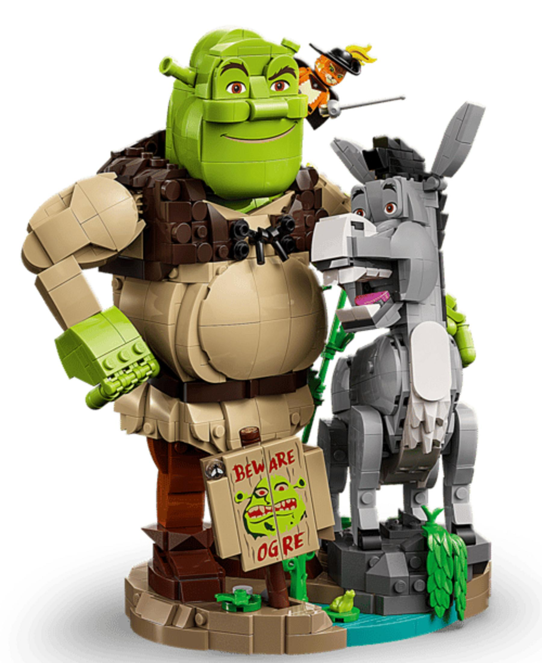 Modele Lego Shreka, Osła i Kota w Butach stoją na ozdobnej podstawie z tabliczką Uwaga Ogr.