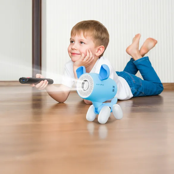 Un ragazzo è sdraiato su un pavimento in legno con un telecomando e un cane robot blu.