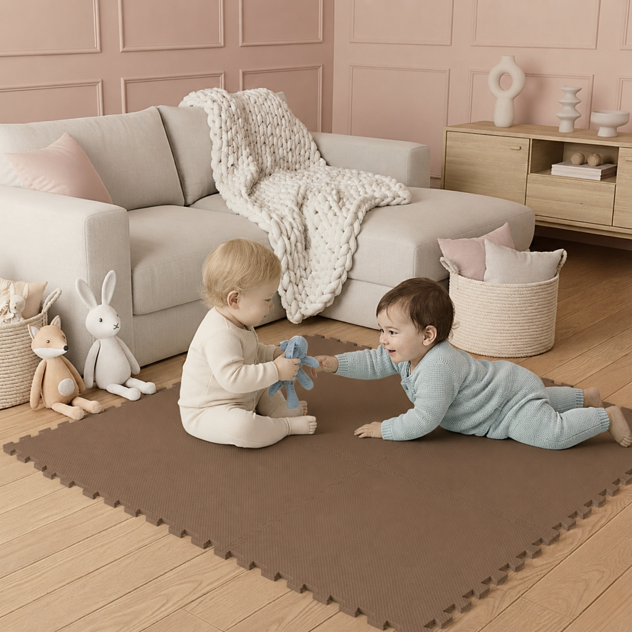 Zwei Babys spielen auf einer braunen Spielmatte vor einer beigefarbenen Couch mit Kuscheltieren.