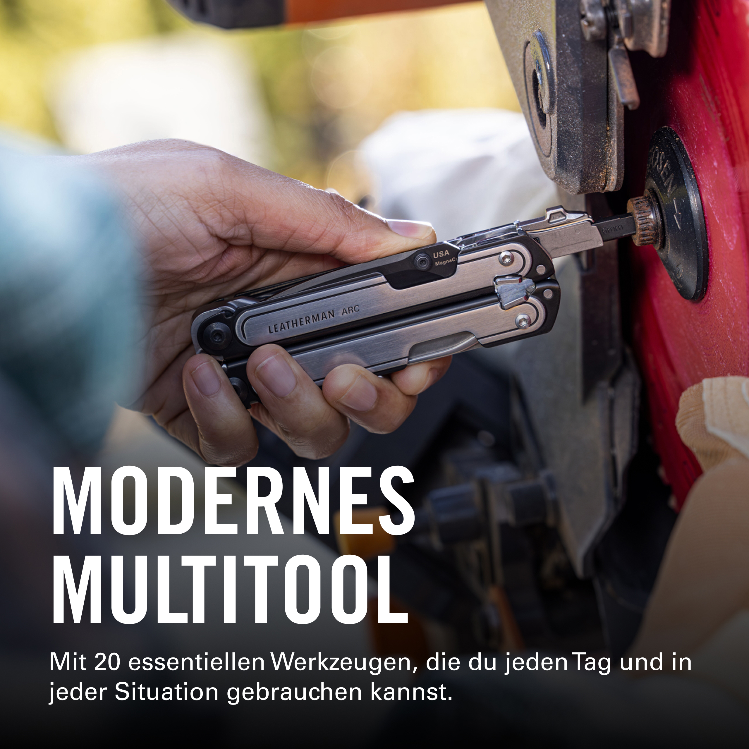 Una mano sostiene una multiherramienta Leatherman Arc plateada mientras usa una punta en una máquina roja.