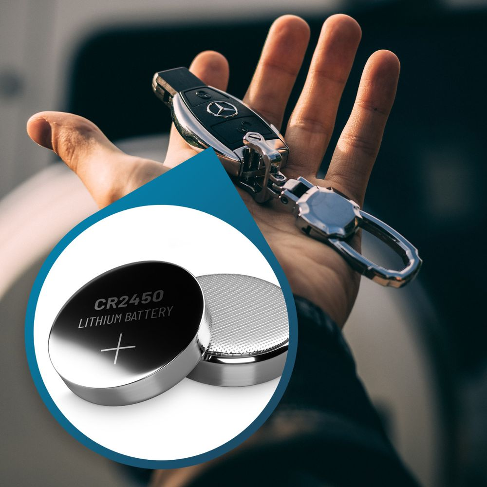 Una mano tiene in mano una chiave dell'auto mentre un cerchio mostra due batterie al litio CR2450.