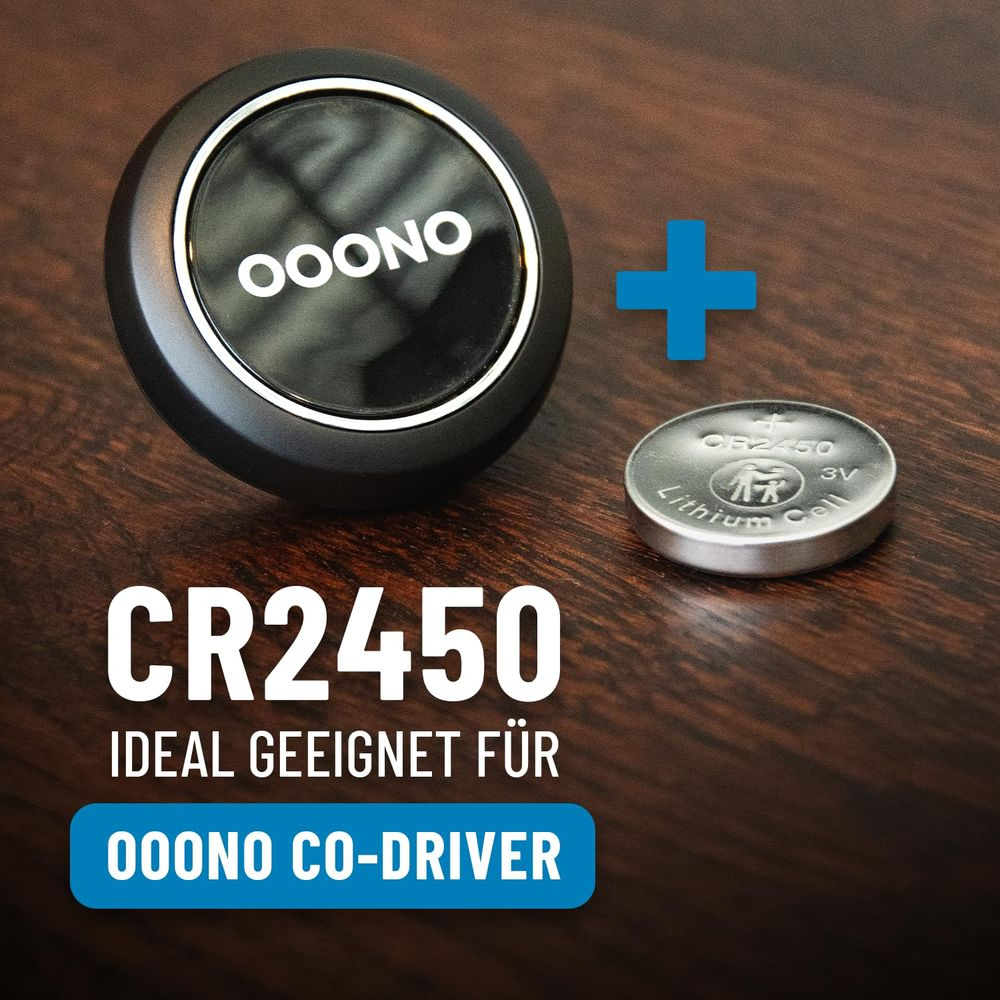 Un dispositivo Ooono Co-Driver e una batteria a bottone CR2450 su un tavolo di legno.