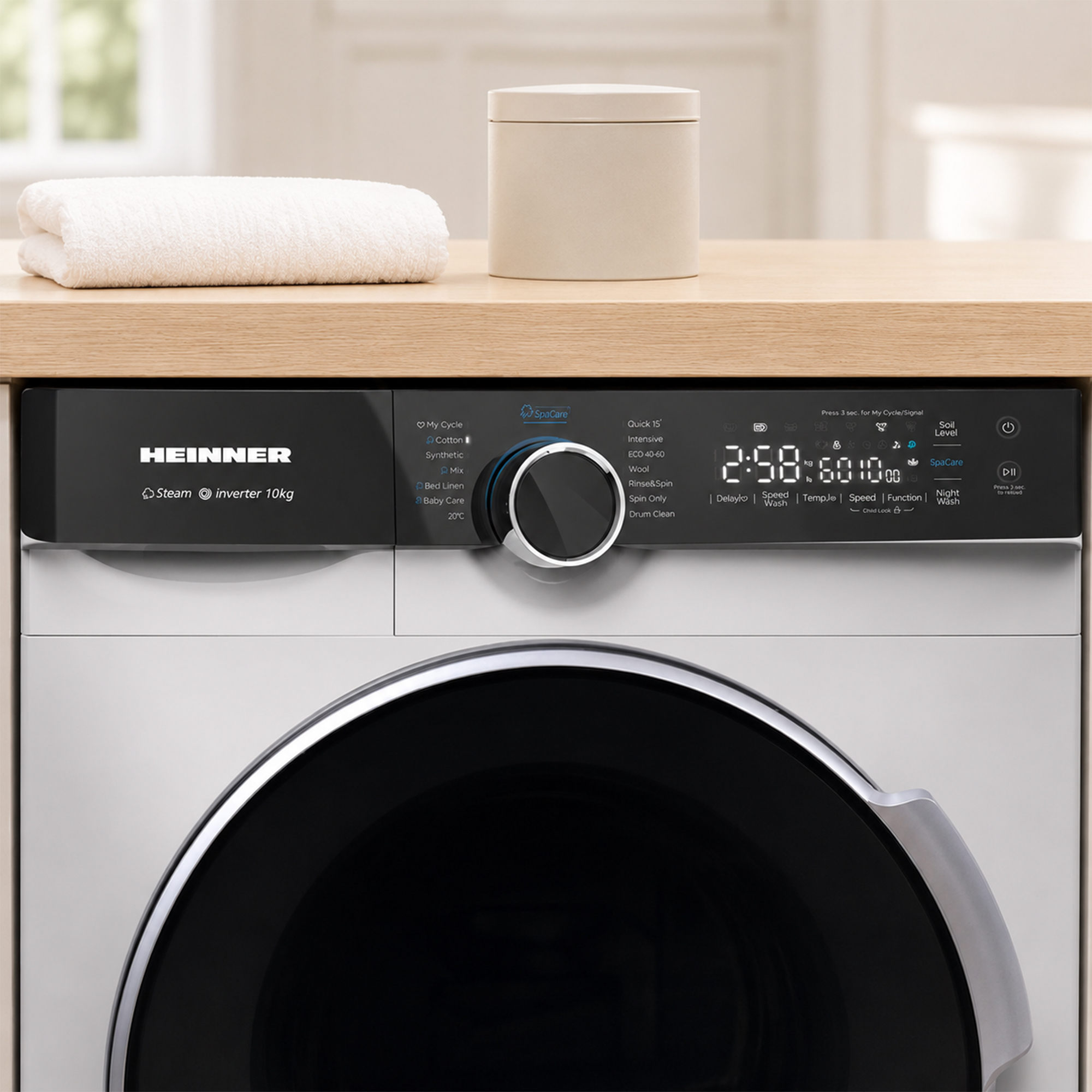 Un lave-linge blanc Heinner avec écran numérique se trouve sous un comptoir en bois avec une serviette et un récipient.