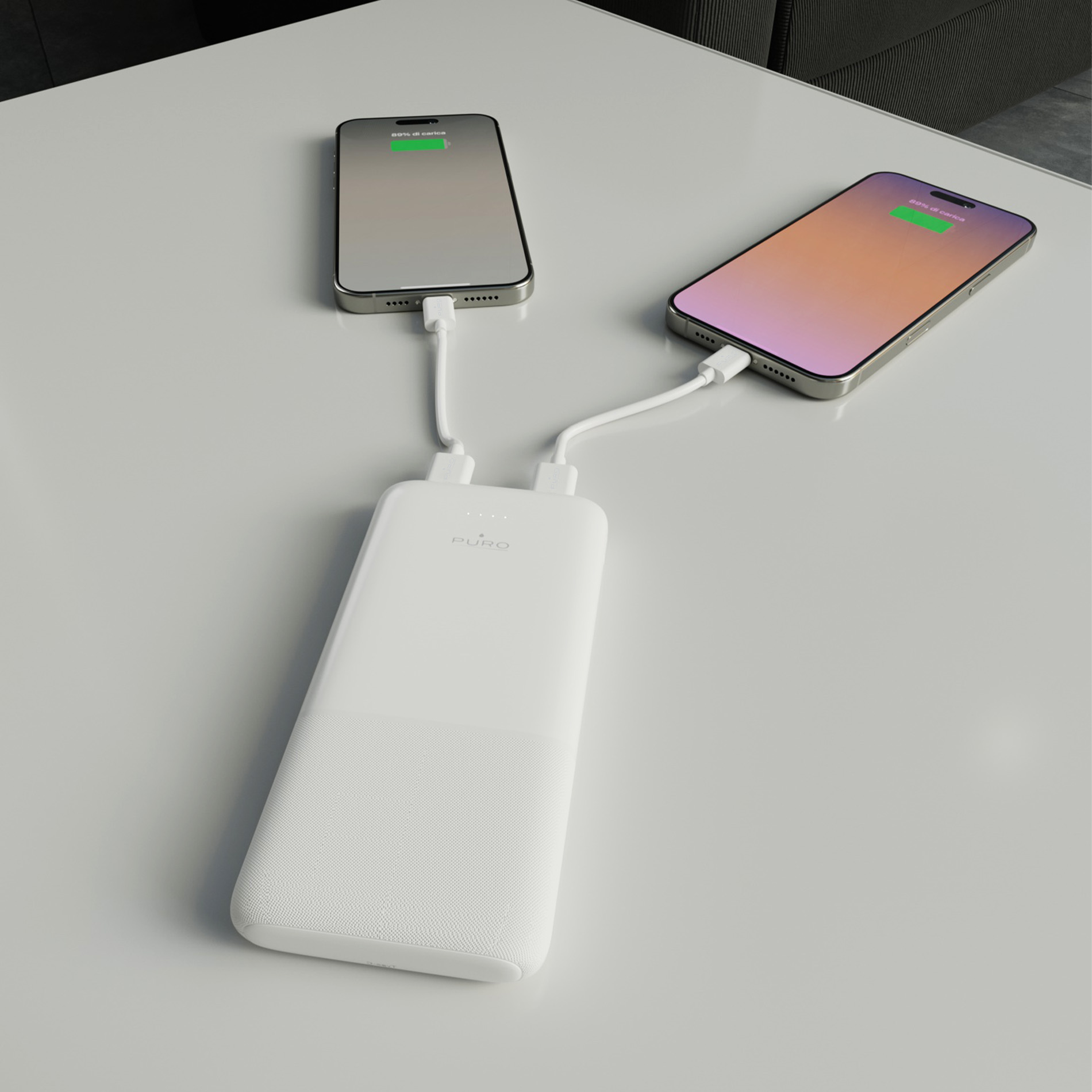 Due smartphone in carica da un power bank bianco Puro su un tavolo.