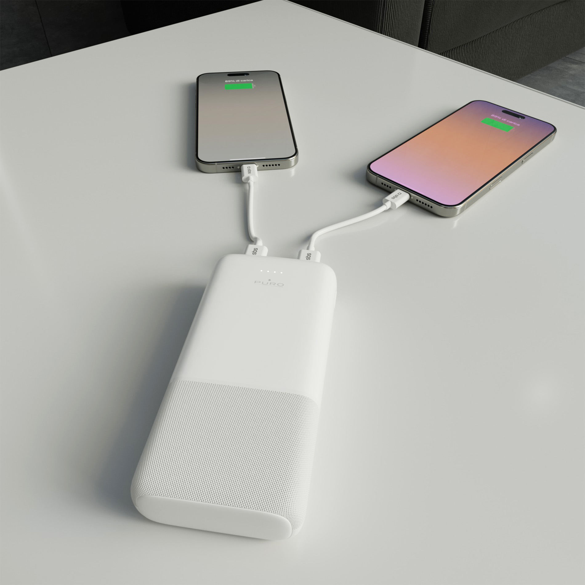 Un power bank bianco su un tavolo bianco ricarica due smartphone.