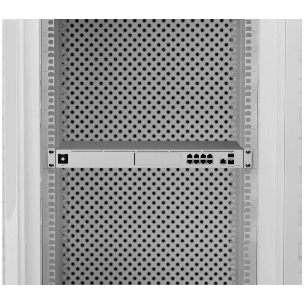Un dispositivo di rete è montato all'interno di un rack per server chiaro con sfondo perforato.