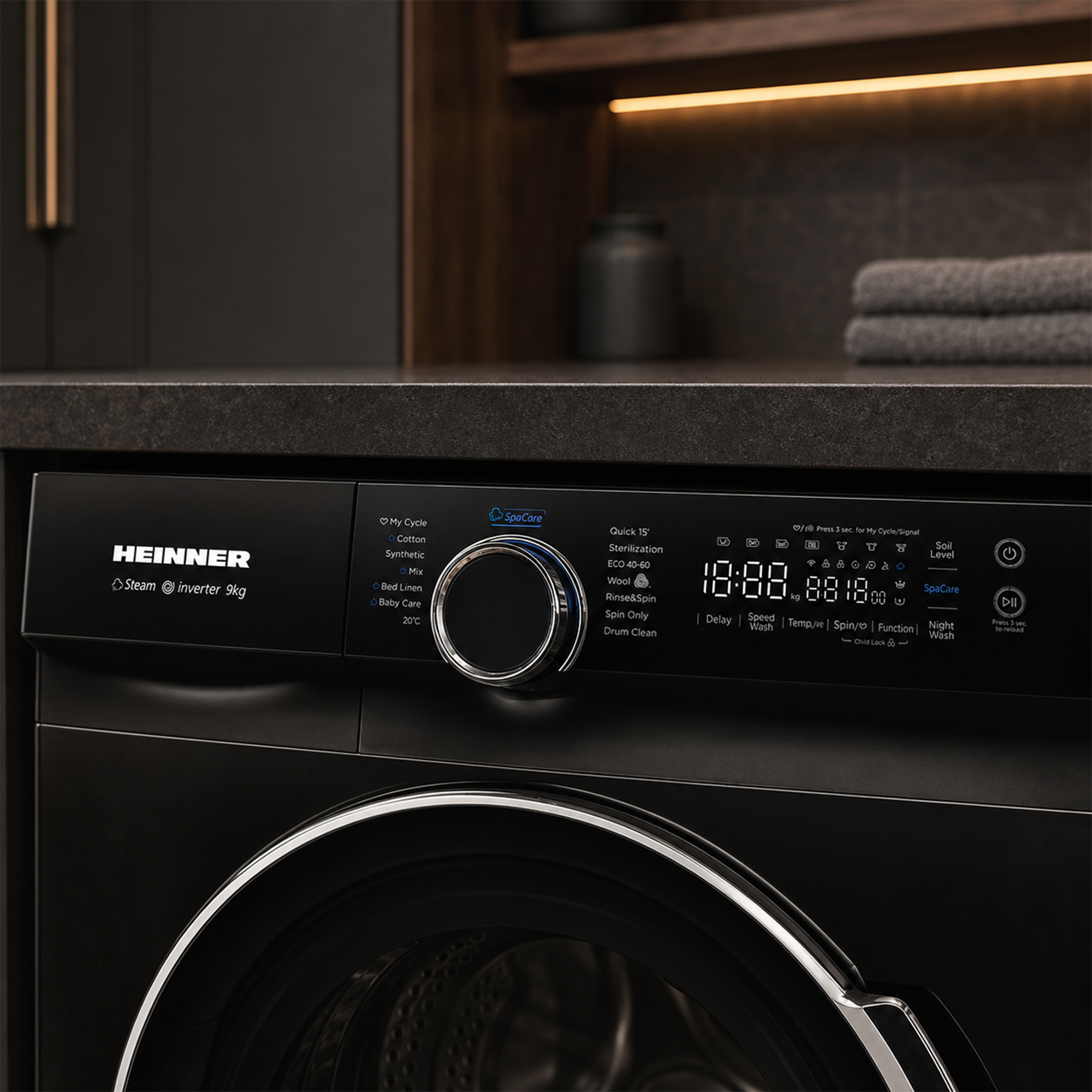Lave-linge noir Heinner avec affichage numérique et bouton rotatif sous un comptoir gris.