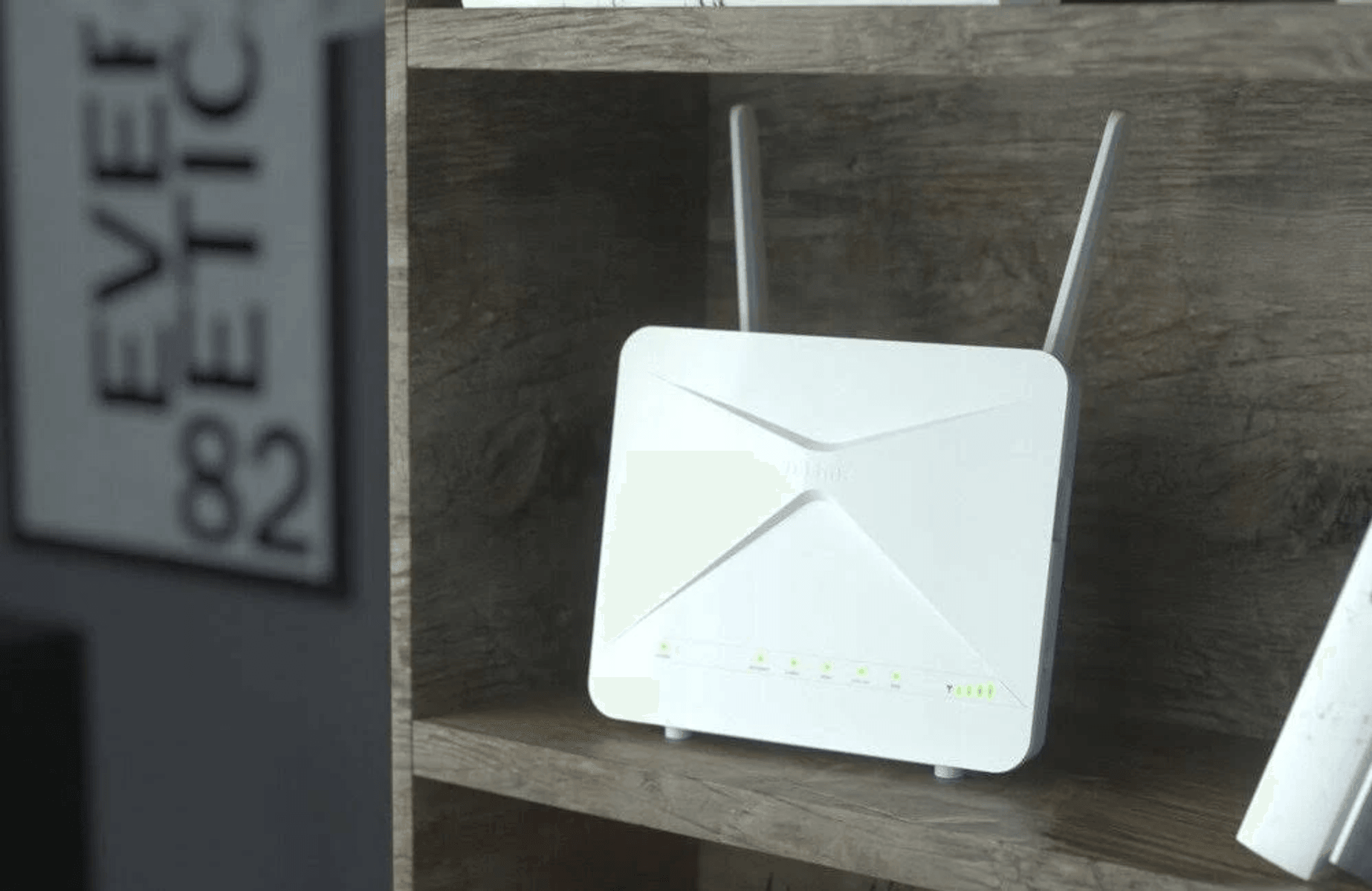 Un router Wi-Fi bianco con due antenne è posizionato su un ripiano di legno.