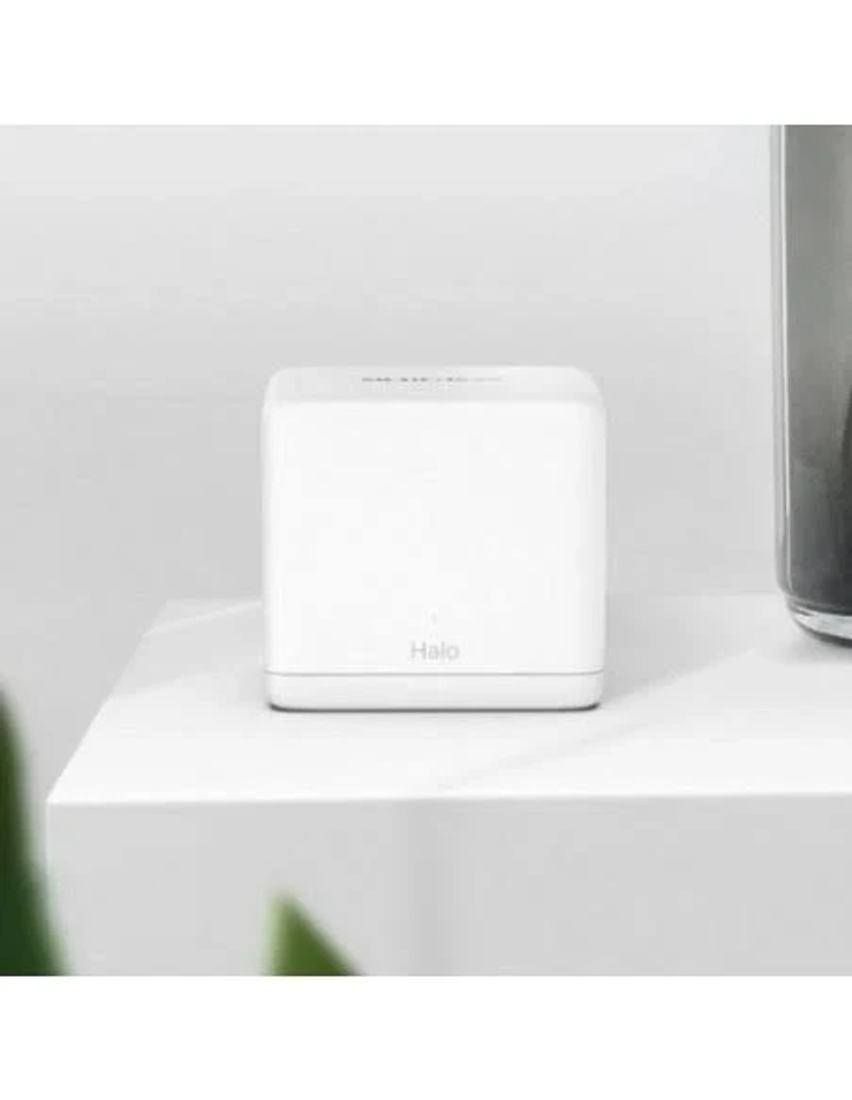 Un altavoz inteligente Halo blanco se encuentra sobre una superficie blanca frente a una pared lisa.
