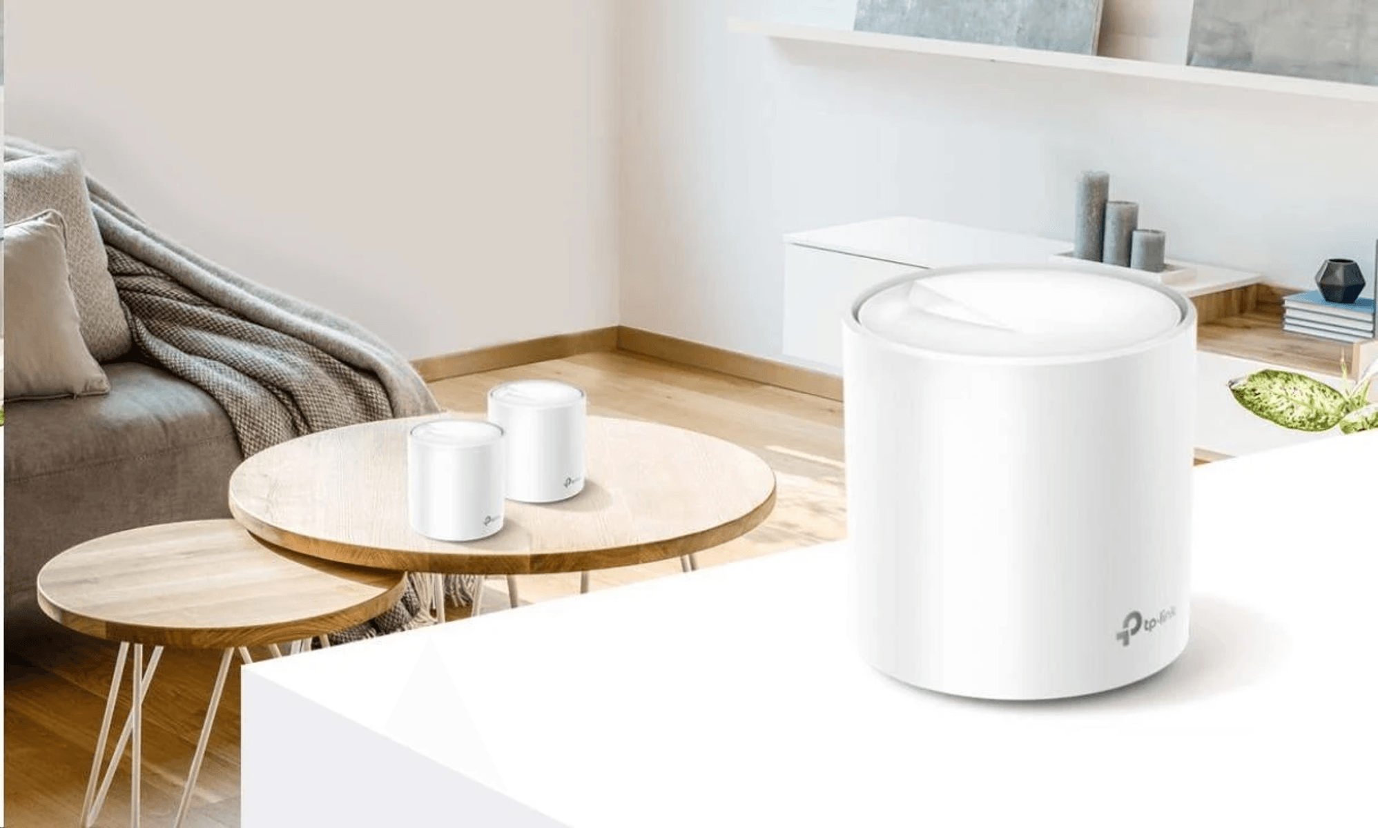 Drei weiße TP-Link-Router stehen in einem hellen Wohnzimmer auf Holztischen und einer weißen Ablage.