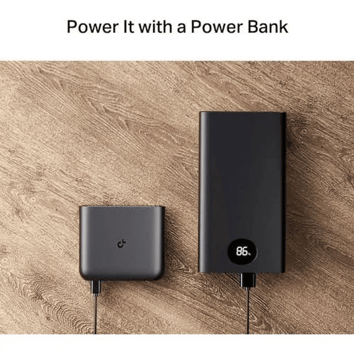 Deux batteries externes noires connectées avec des câbles reposent sur une surface en bois.