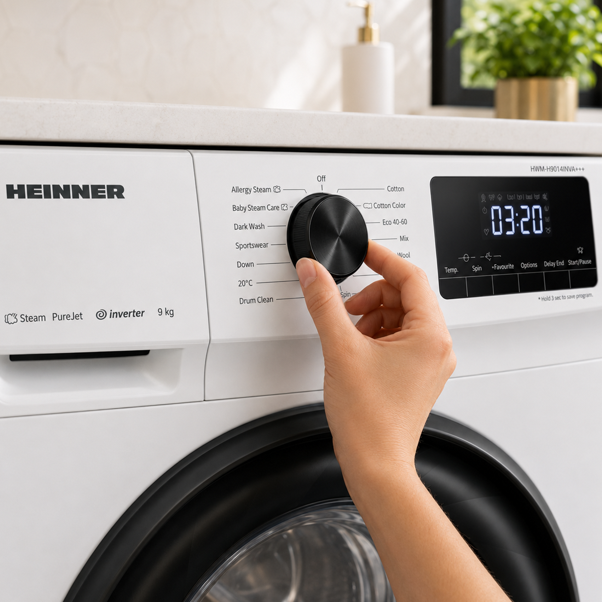 Une main tourne le sélecteur de programme noir d'un lave-linge blanc Heinner.