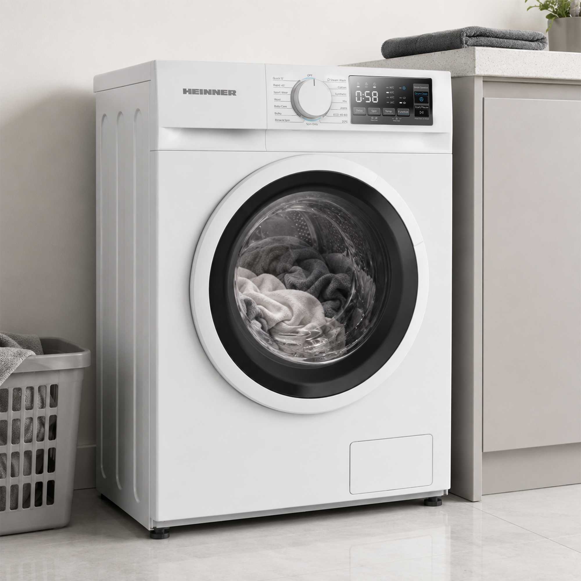 Un lave-linge blanc Heinner chargé de linge dans une cuisine moderne, avec un panier gris.