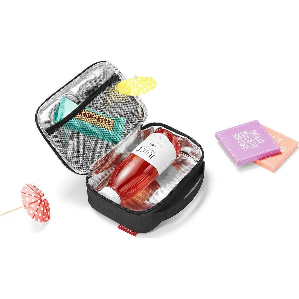 Eine offene schwarze Isoliertasche mit rotem Saft, einem Riegel, kleinen Schachteln und zwei bunten Cocktailschirmen.