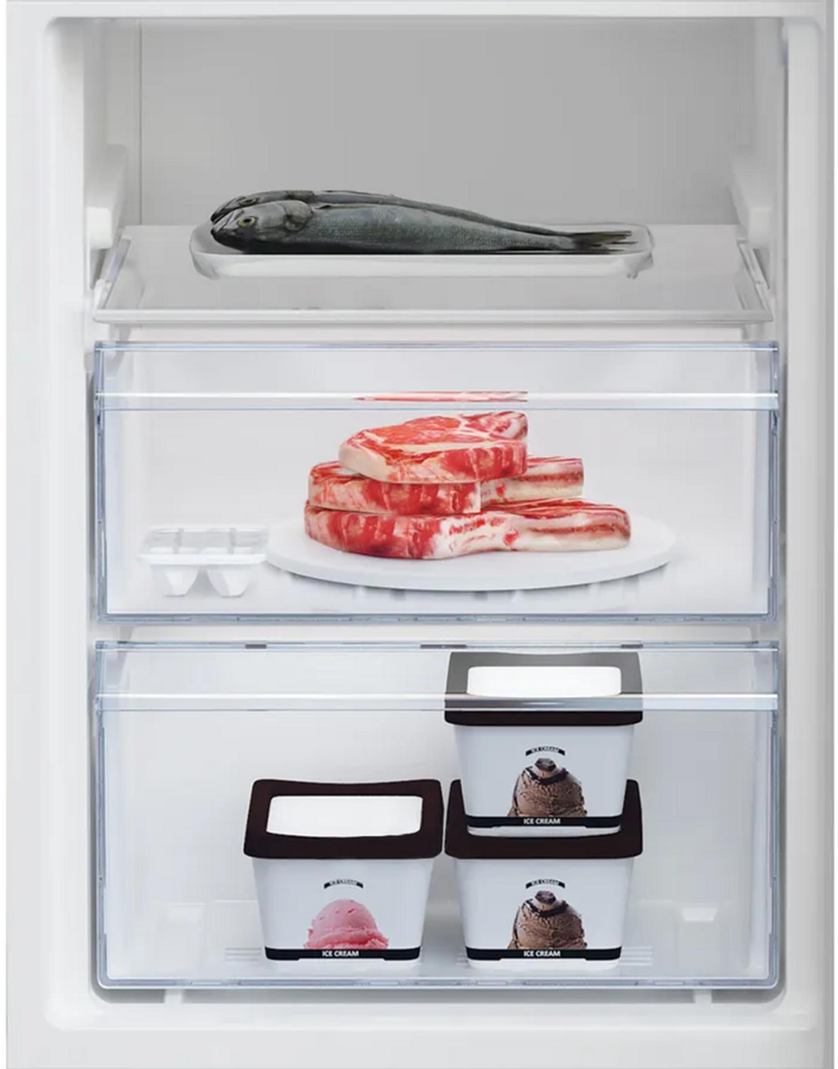 Un congelatore bianco con pesce sul ripiano superiore, carne nel cassetto centrale e vaschette di gelato in basso.