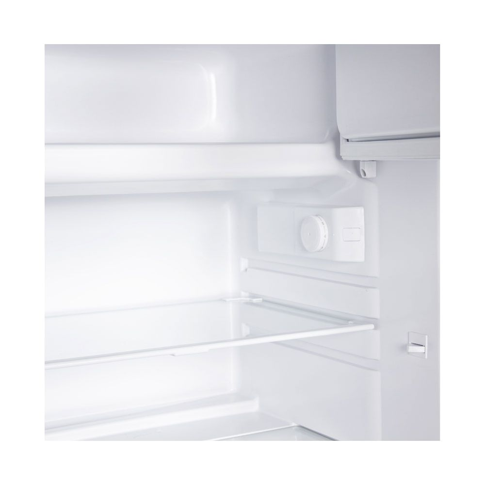 L'interno di un frigorifero bianco vuoto con ripiano in vetro e manopola della temperatura.