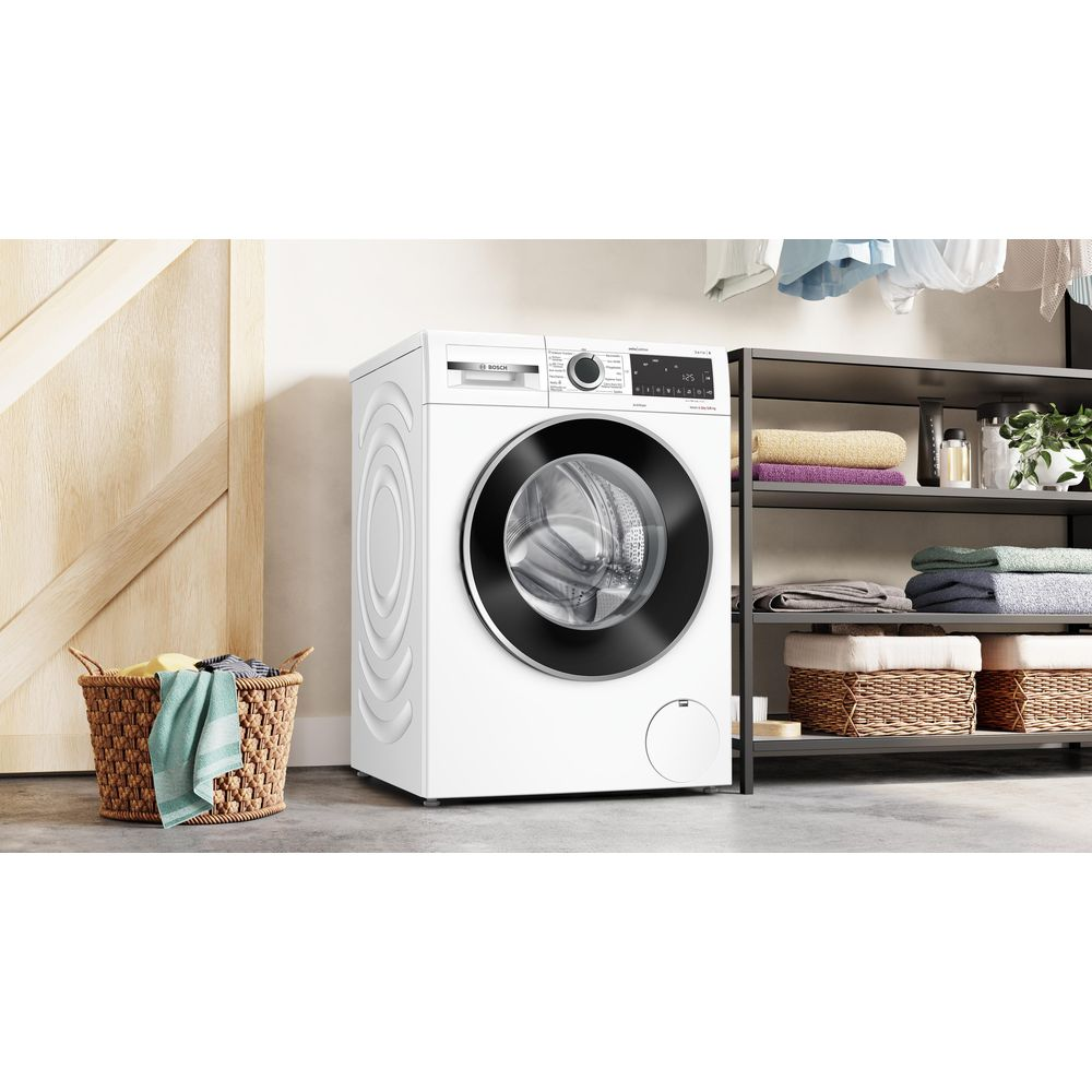 Un lave-linge blanc dans une pièce, avec un panier à linge et une étagère de serviettes à proximité.