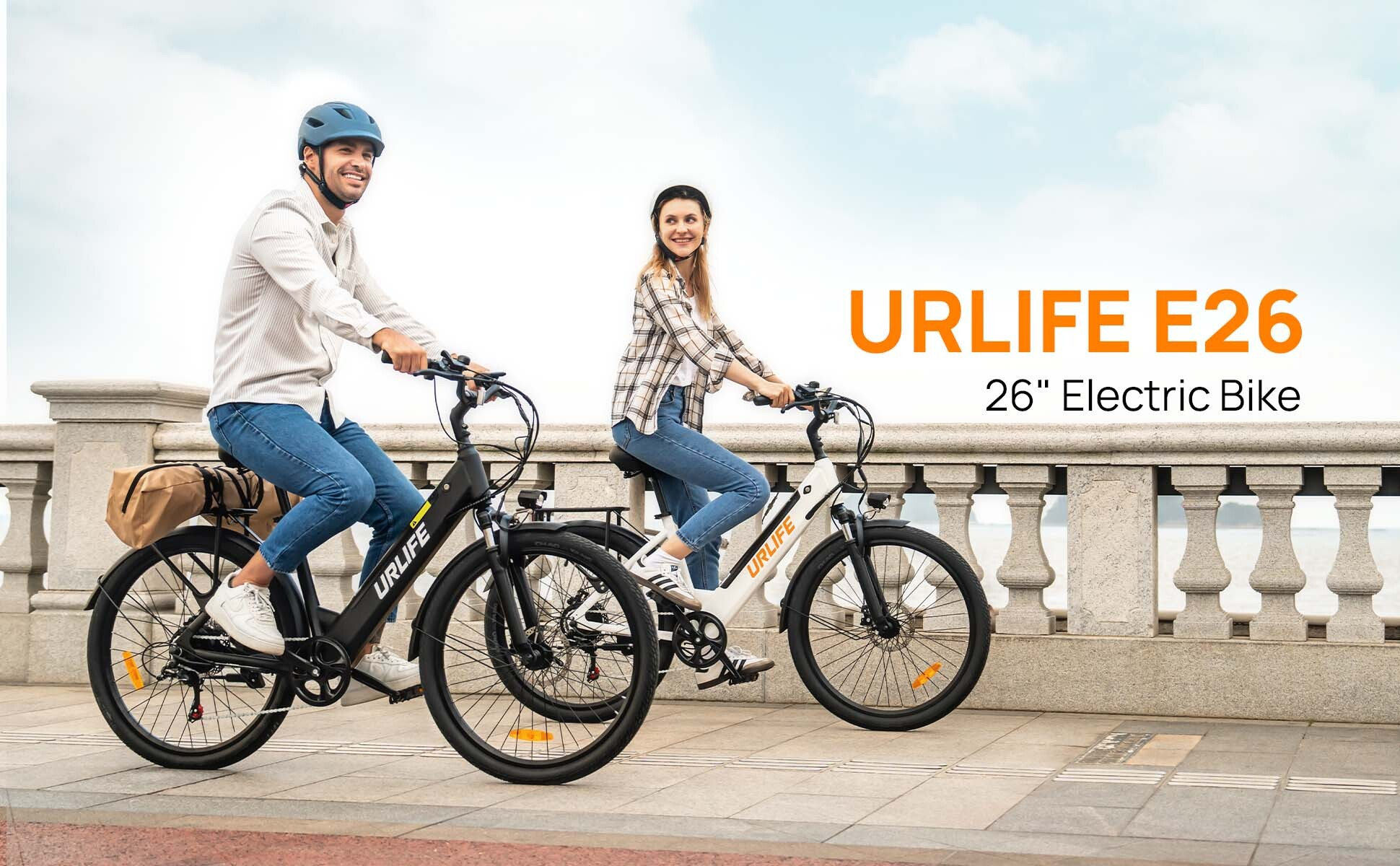 Una coppia sorridente guida bici elettriche URLIFE E26 lungo un muro della passeggiata.