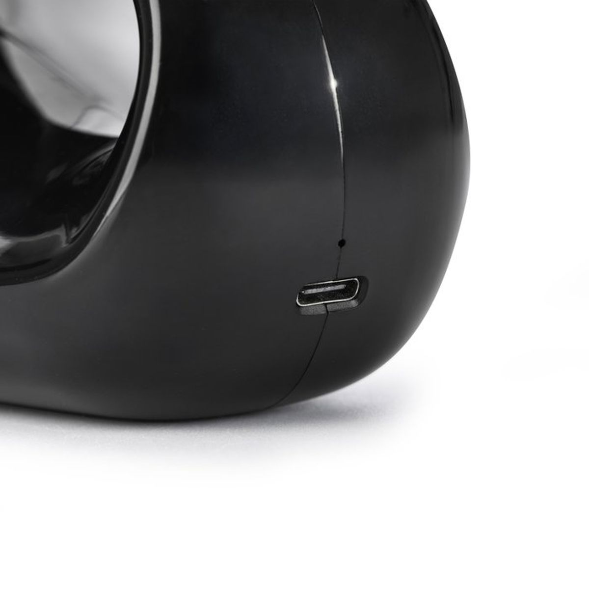 Ein schwarzes glänzendes Gerät mit einem sichtbaren USB-Anschluss auf der Unterseite gegen einen weißen Hintergrund.