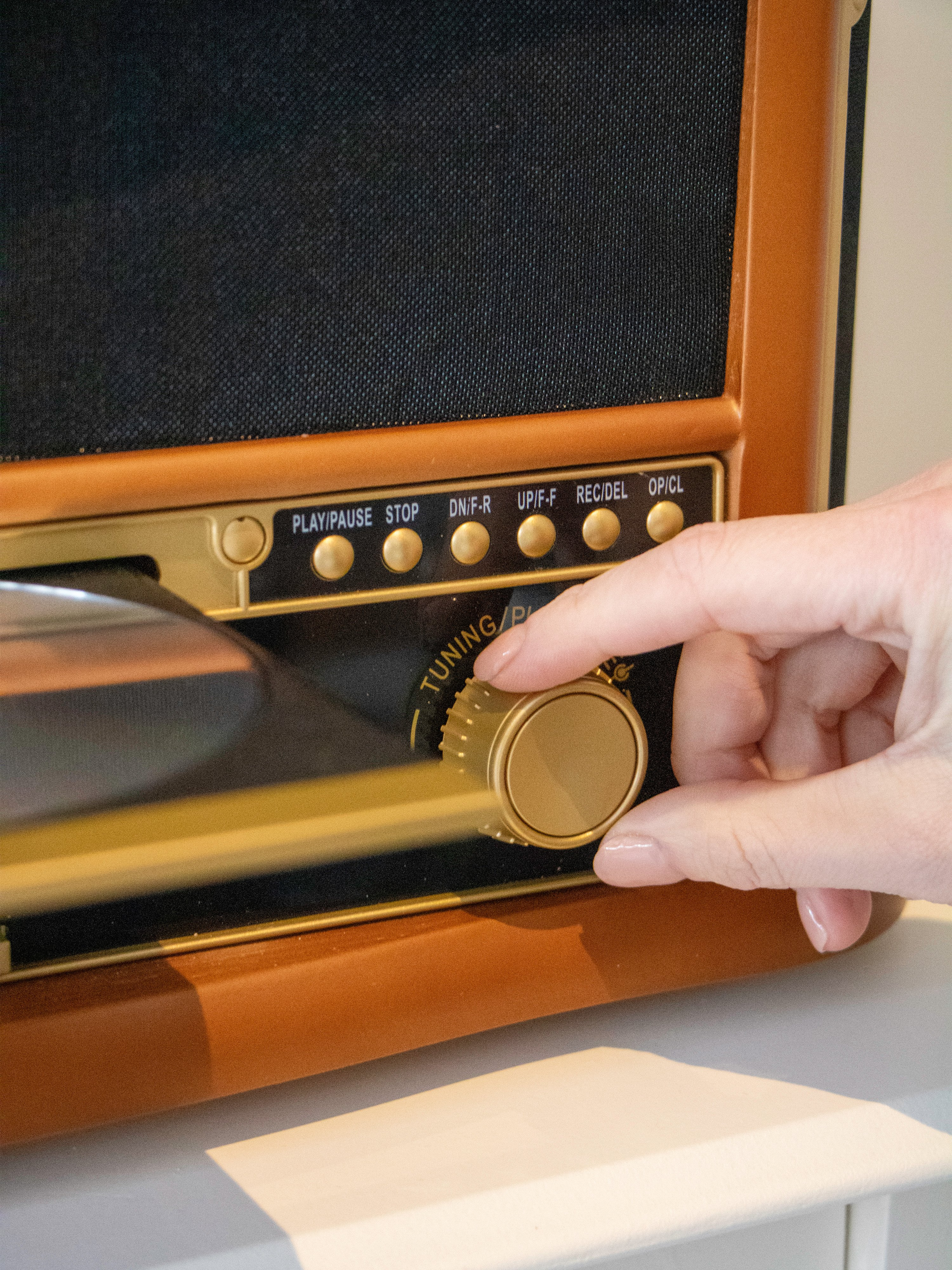 Eine Hand dreht den goldenen Regler eines braunen Retro-Radios.