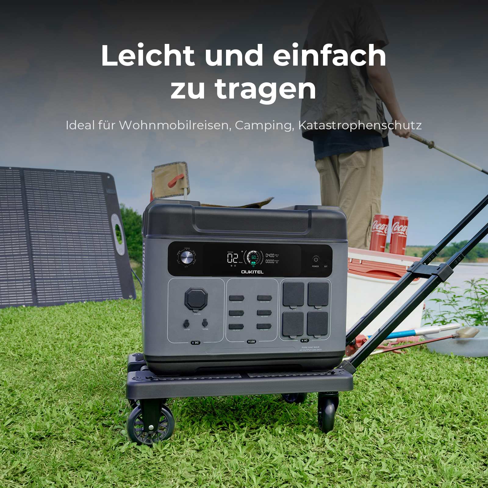 Ein graues Oukitel-Kraftwerk steht auf einem kleinen Wagen im Gras mit einem Solarmarkt im Hintergrund.