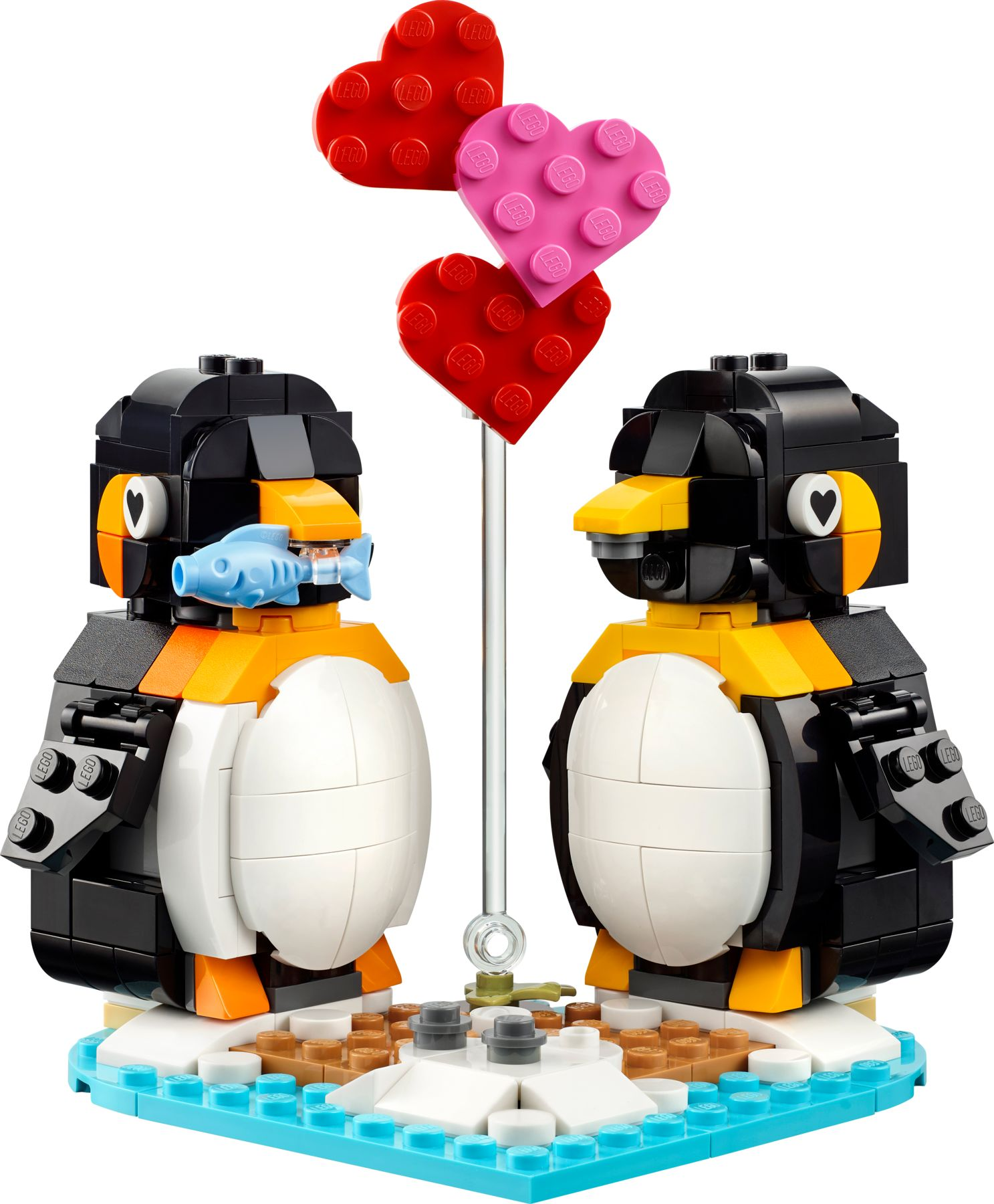 Zwei LEGO Pinguine mit Herzen auf einer blauen Basis, einer hält einen blauen Fisch.