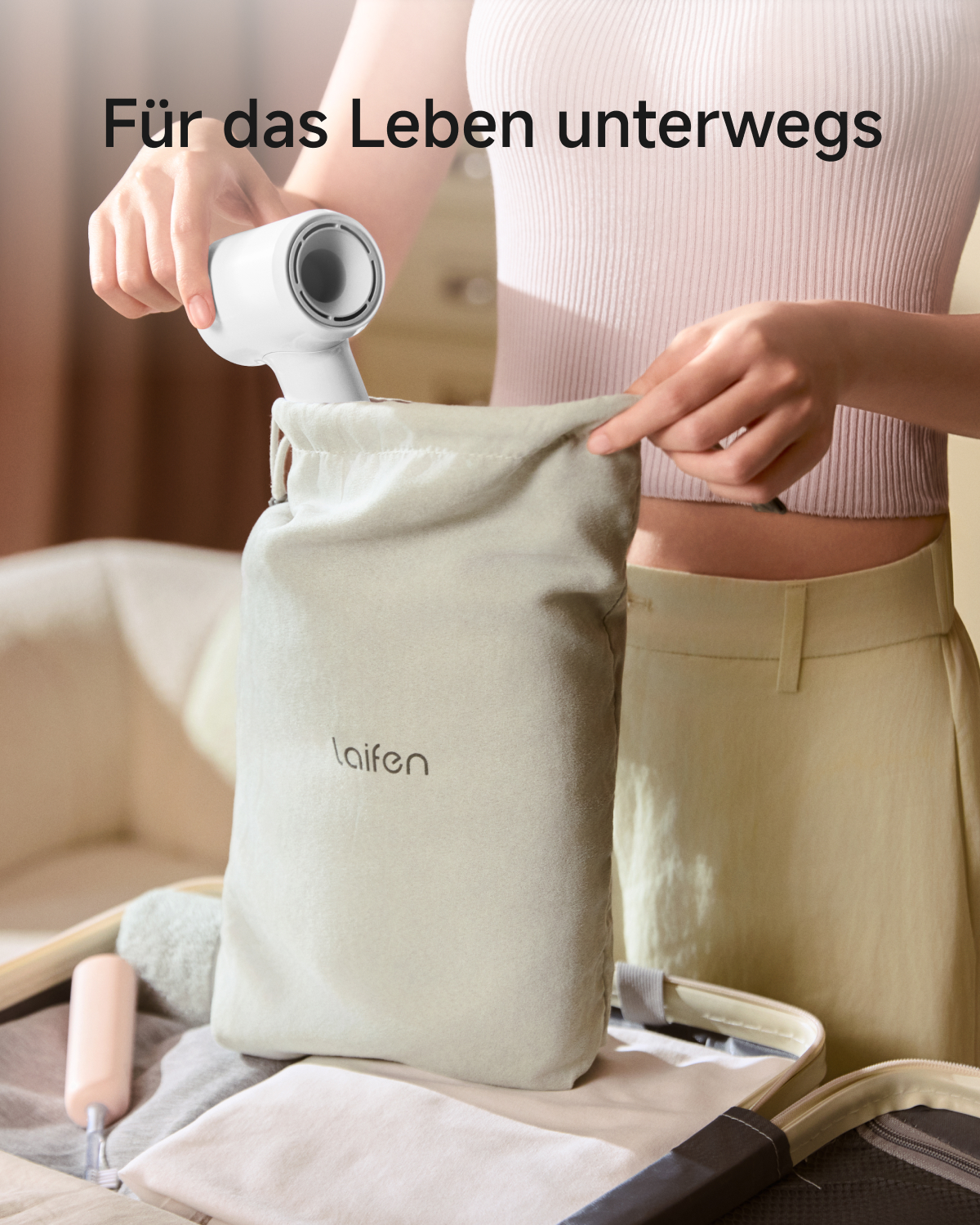Eine Frau packt einen weißen Föhn in einen beigen Beutel mit der Aufschrift Laifen, Text: Für das Leben unterwegs.