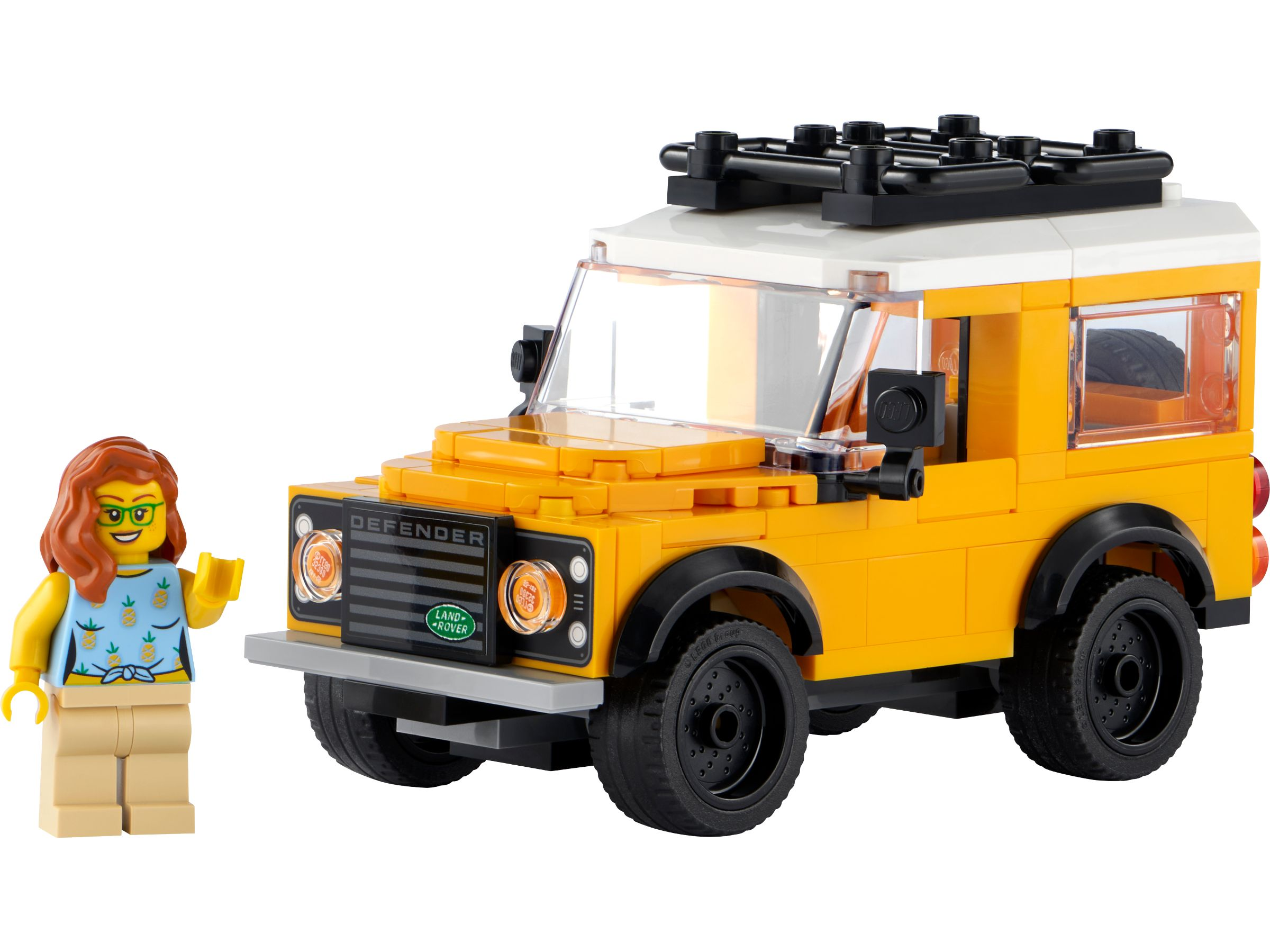 Ein gelb-weißer Lego Land Rover Defender neben einer Lego-Minifigur mit Ananas-Shirt.