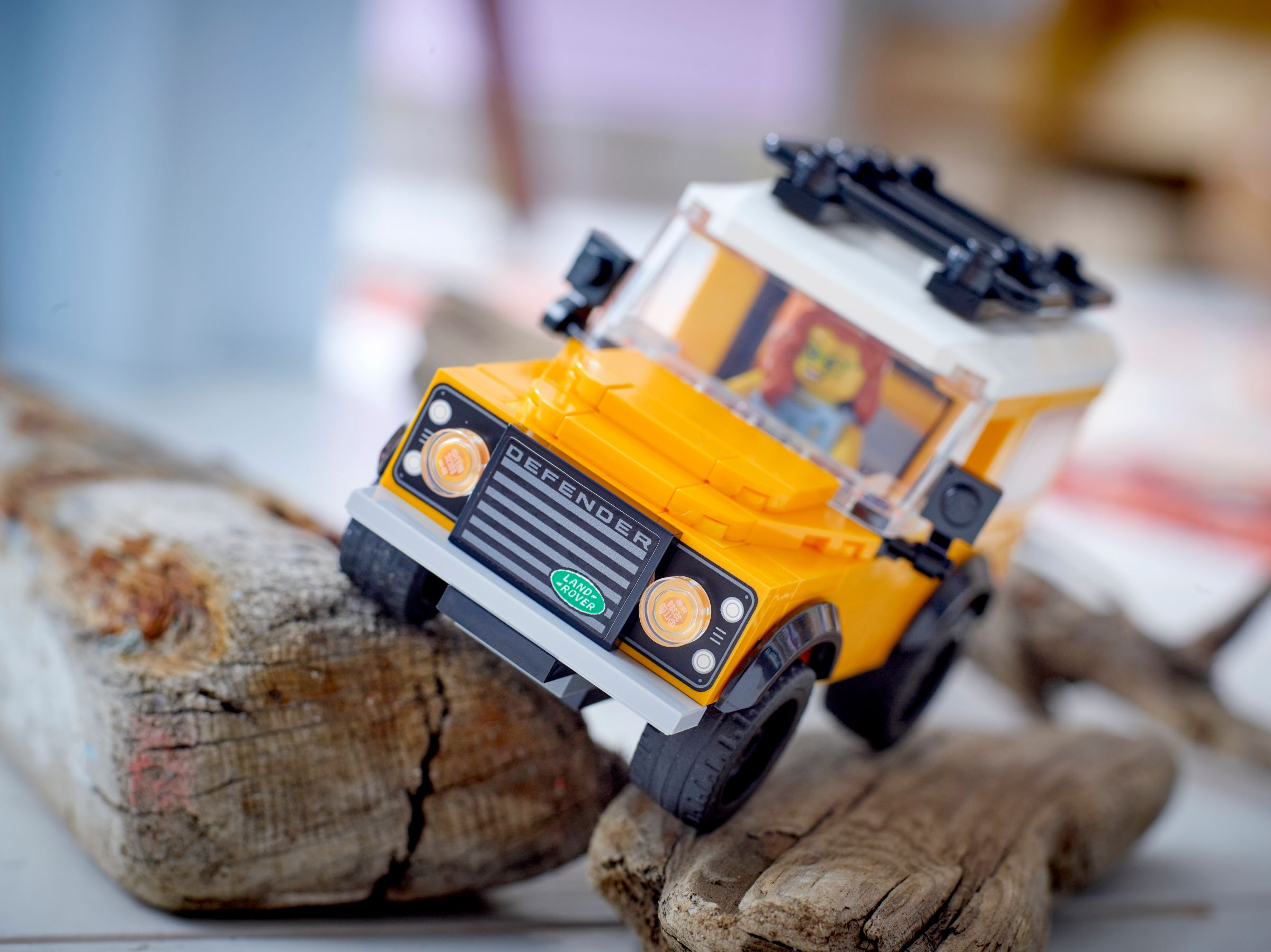 Ein gelbes Lego Land Rover Defender Modell fährt über Äste.