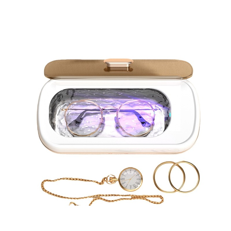 UV-Sterilisatorbox mit Brille darin, begleitet von einer Taschenuhr an Kette und zwei goldenen Ringen.