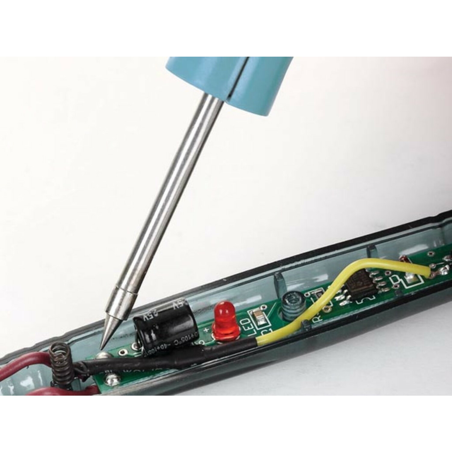 Lötkolbenspitze berührt eine grüne Leiterplatte mit elektronischen Bauteilen.