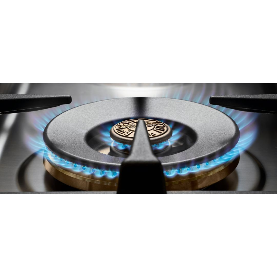 Un bruciatore a gas acceso con fiamme blu vive sotto una griglia nera.