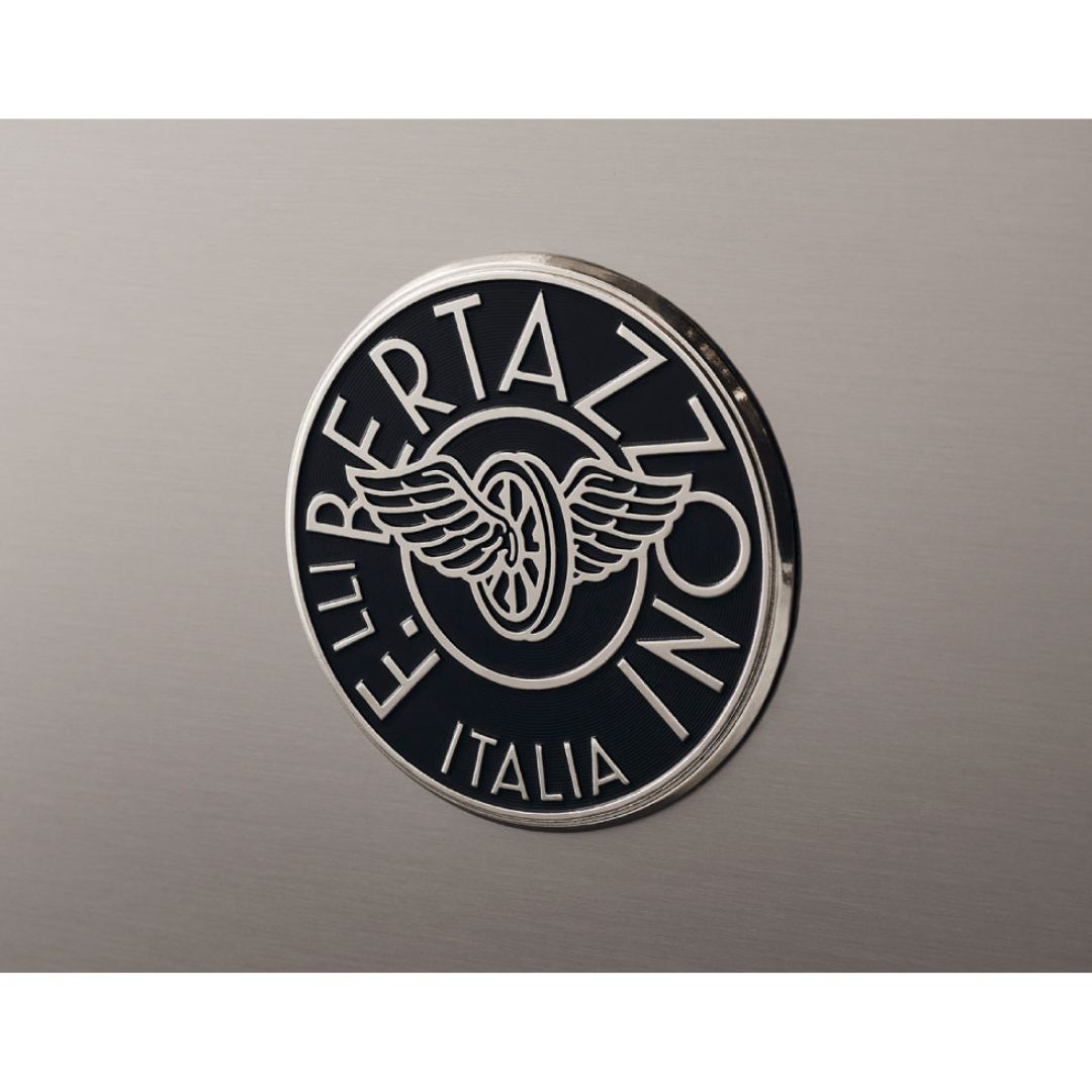 Logo rotondo argento e nero Bertazzoni con ali e ruote su acciaio inossidabile spazzolato.
