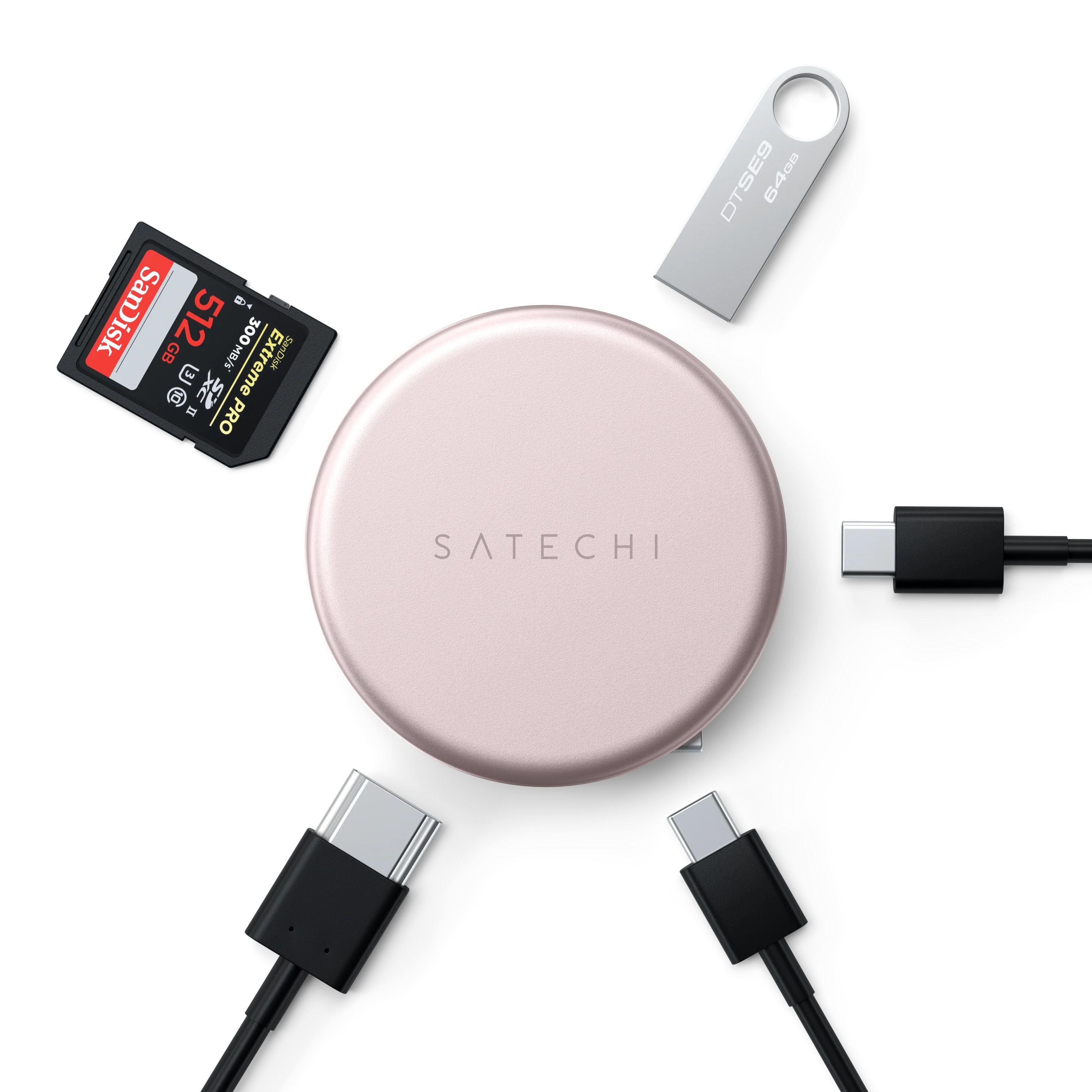 Różowozłoty okrągły hub Satechi w otoczeniu kabli USB, karty SD i pendrive'a na białym tle.