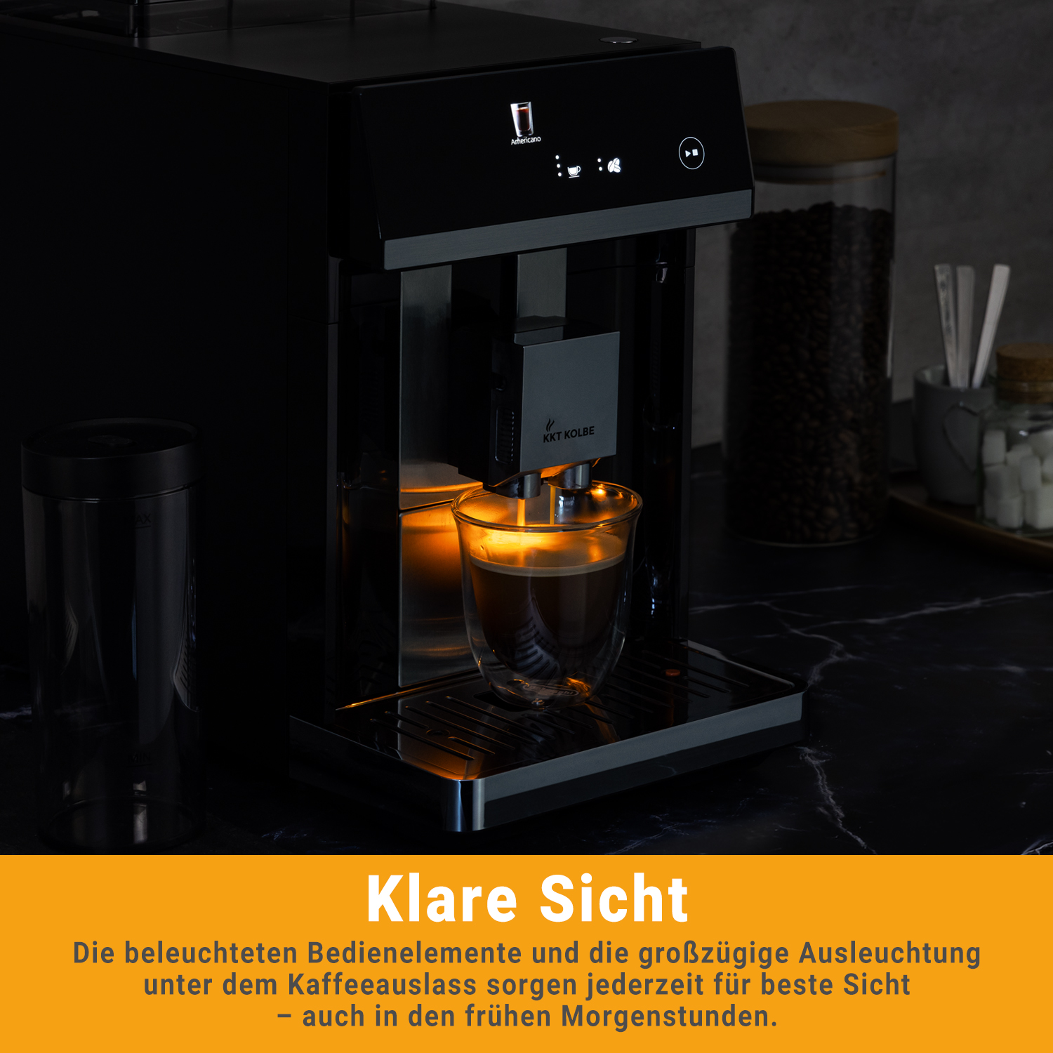 Moderna macchina da caffè con beccuccio illuminato e tazza di vetro con caffè su piano di lavoro scuro.