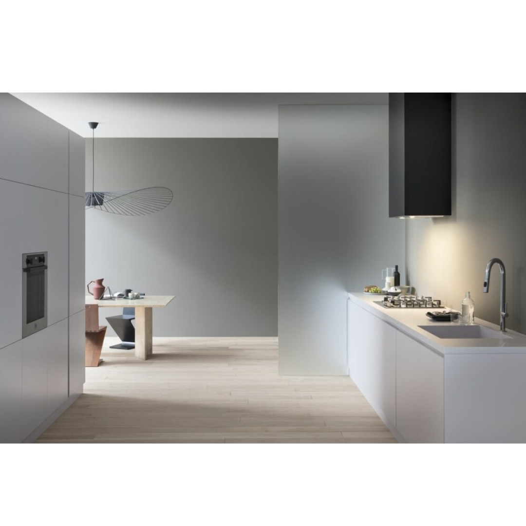 Una cucina moderna e minimalista in bianco e grigio con pavimento in legno e un tavolo da pranzo sullo sfondo.