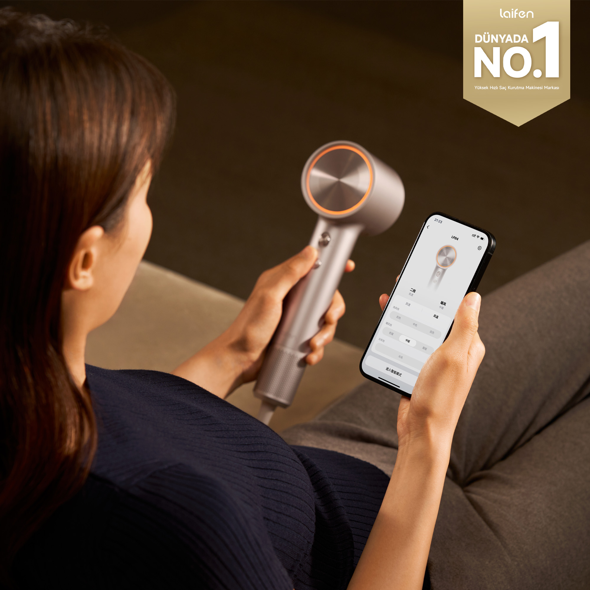 Bir kadın modern gümüş saç kurutma makinesi ve kontrol ayarları gösteren akıllı telefon tutuyor.