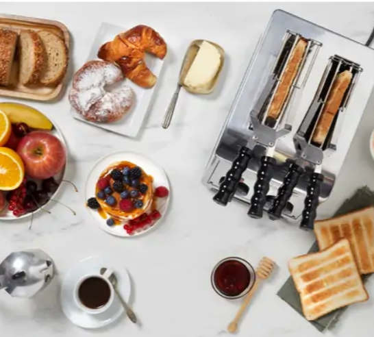 Top-Ansicht eines Frühstückstischs mit Toaster, Toast, Gebäck, frischem Obst, Butter und Kaffee.