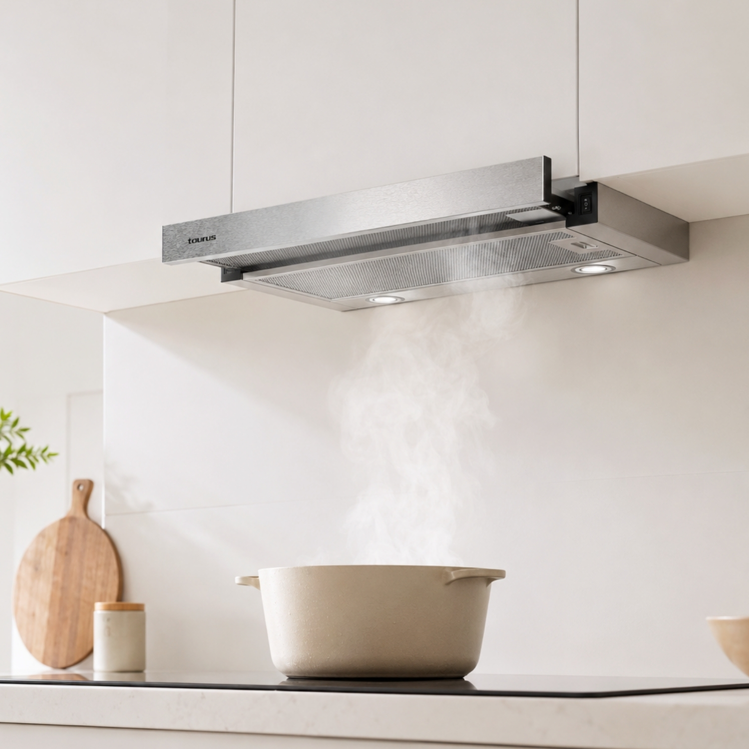 Una olla beige en una estufa con vapor espeso que sube a una campana extractora plateada en una cocina blanca.