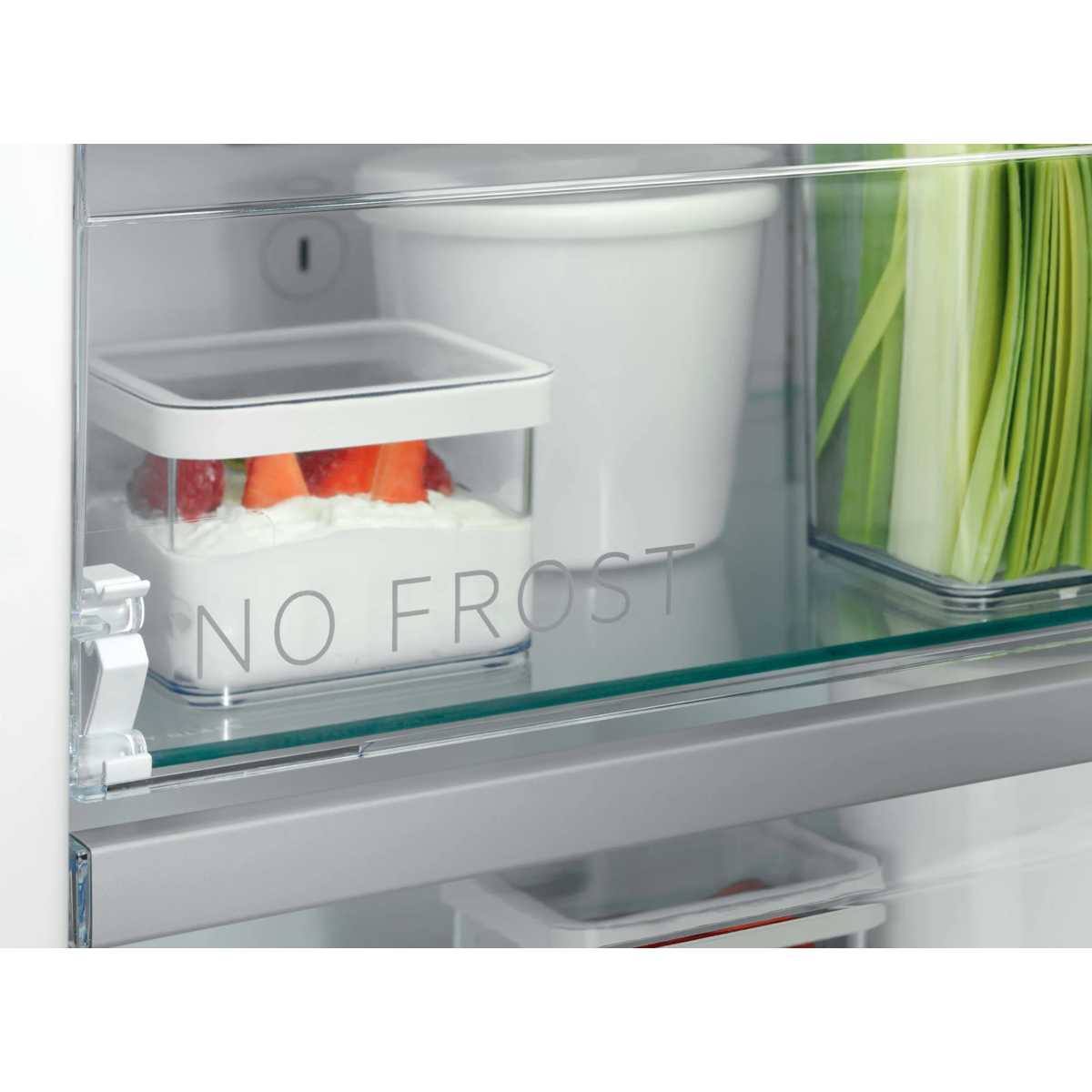 Interior de un refrigerador con texto No Frost, estantes de vidrio, recipientes con fresas y hierbas.
