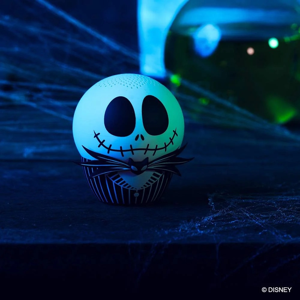 Örümcek ağlarıyla kaplı karanlık bir zeminde çizgili takım elbiseli ve papyonlu aydınlatılmış Jack Skellington figürü.