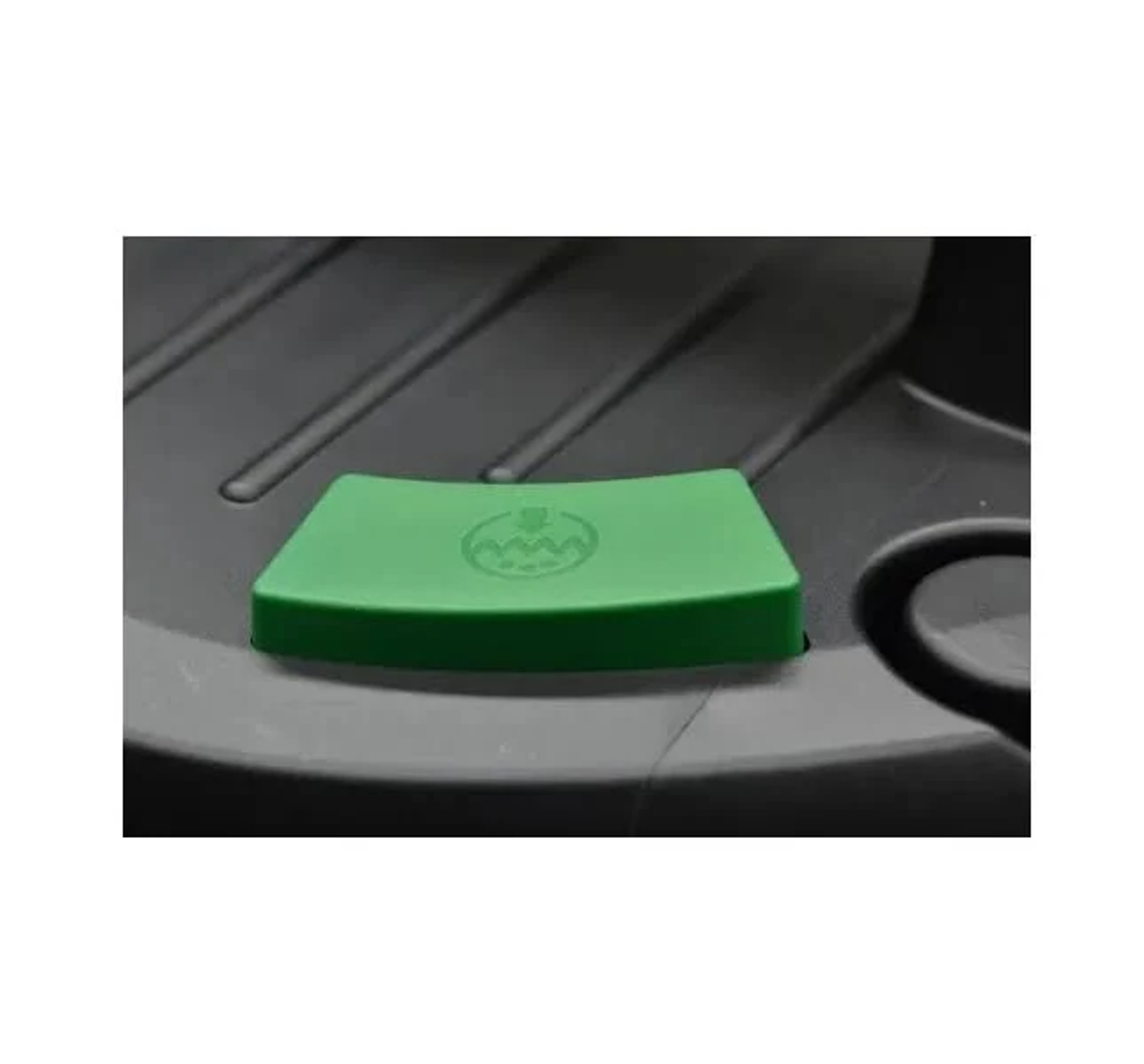 Un pulsante verde trapezoidale con un simbolo a onde su una superficie in plastica nera.