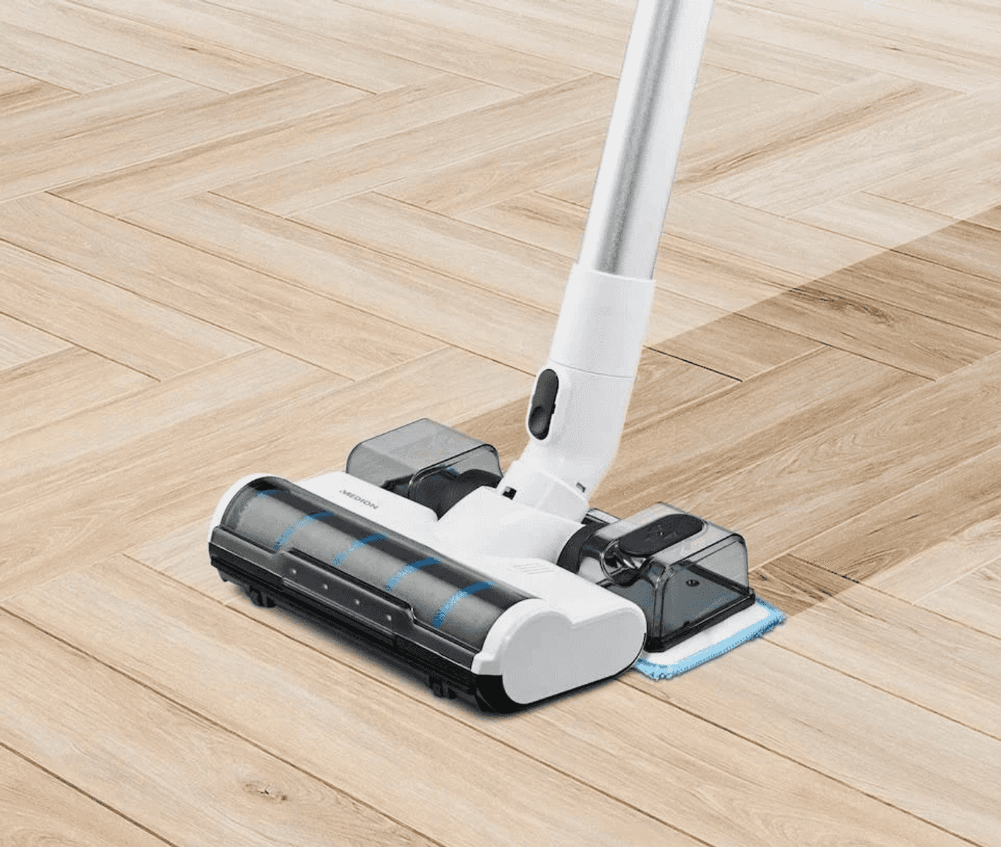Un pulitore per pavimenti senza fili bianco e nero pulisce un pavimento in legno chiaro a spina di pesce.