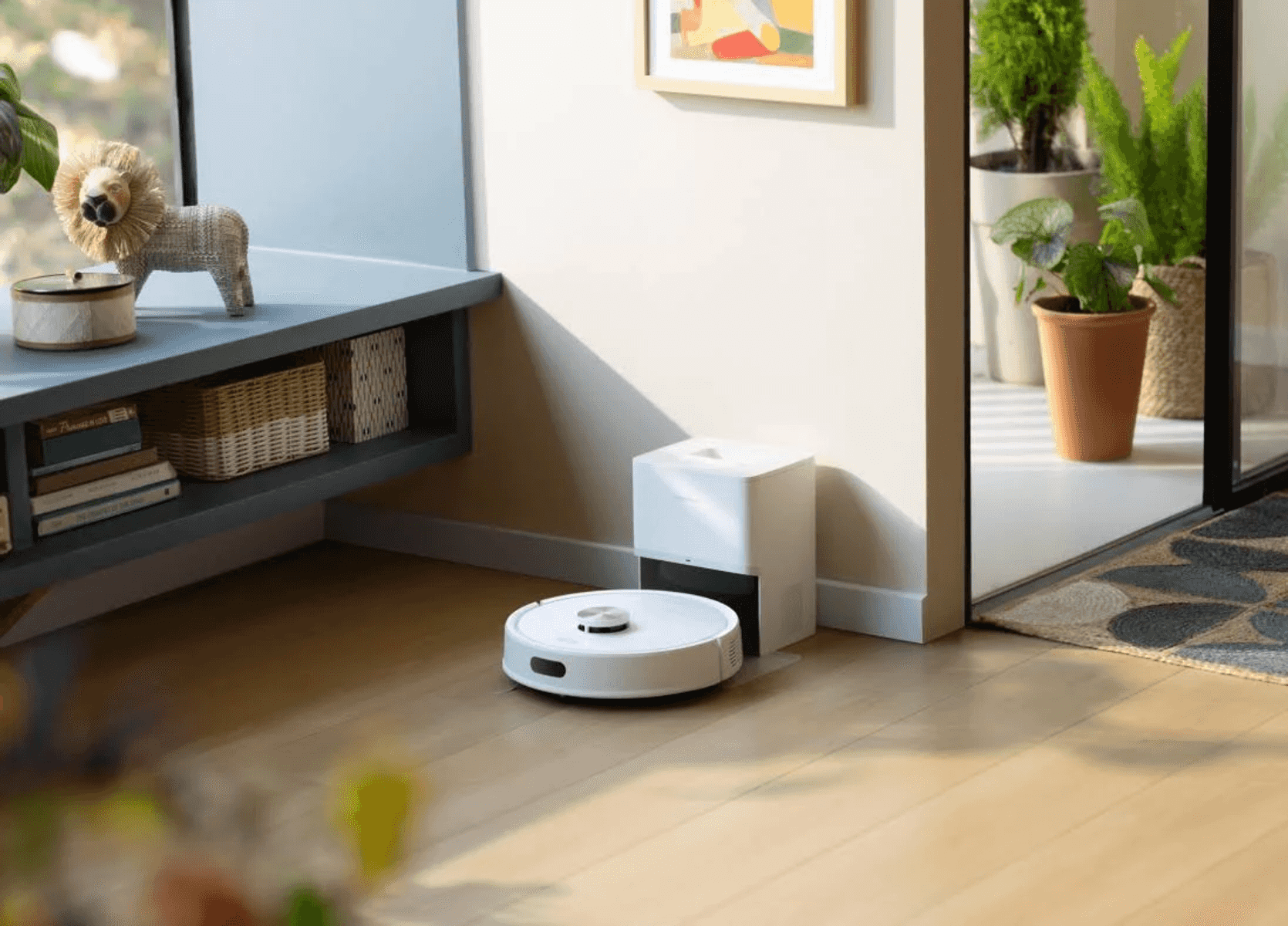 Un robot aspirapolvere bianco è posizionato sul pavimento in legno davanti alla sua base.