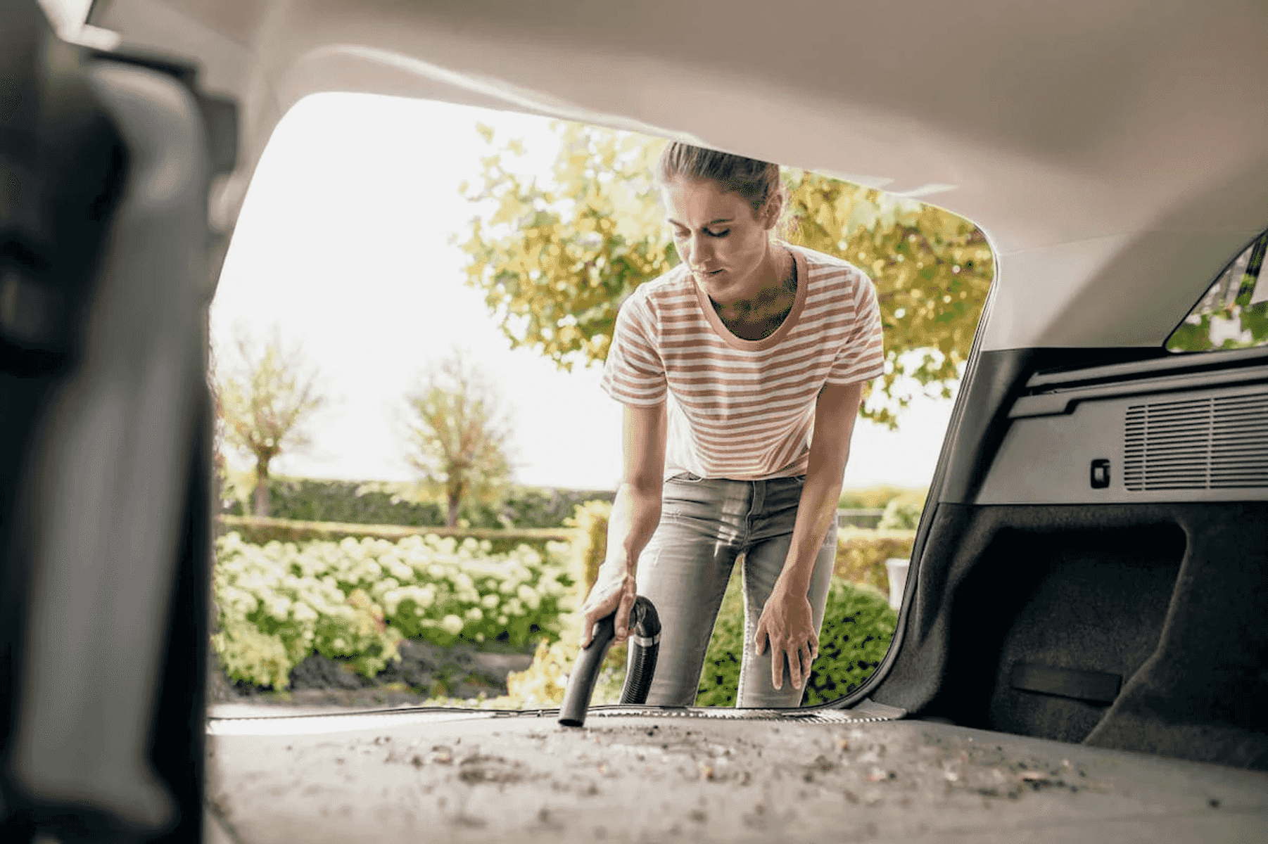 Una donna aspira il bagagliaio della sua auto pieno di detriti all'aperto.