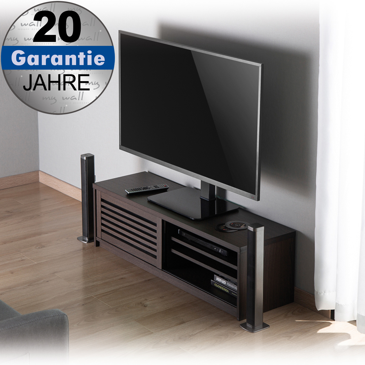 Ein Fernseher steht auf einem dunklen TV-Schrank in einem Raum mit Holzboden, flankiert von Lautsprechern.