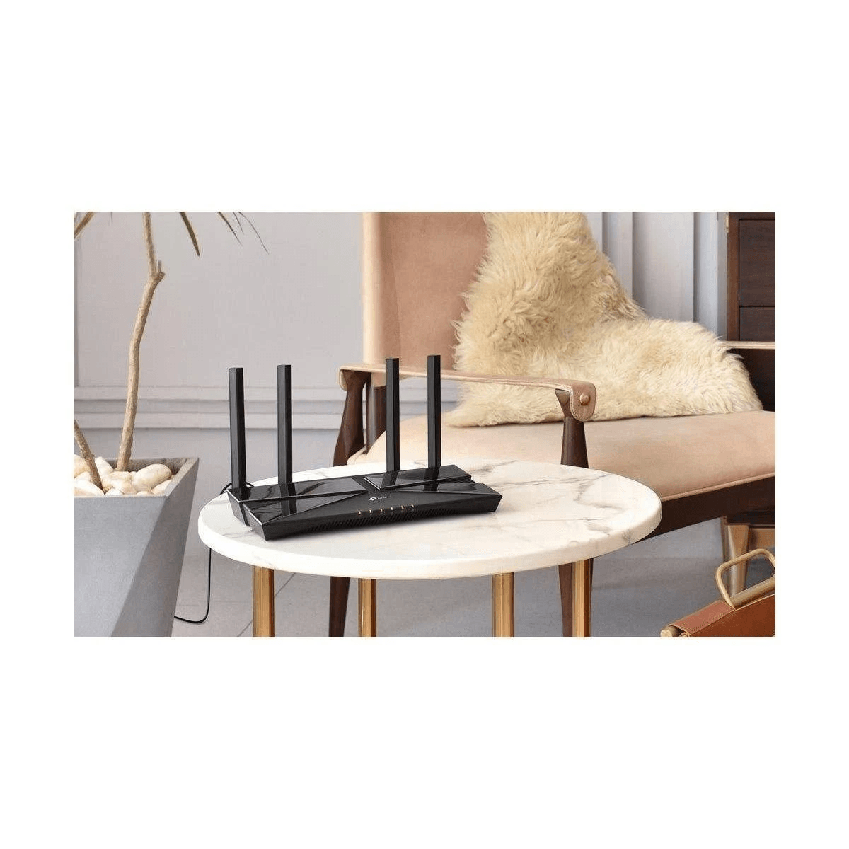 Un router Wi-Fi negro con cuatro antenas está sobre una mesa redonda de mármol en una habitación luminosa y moderna.