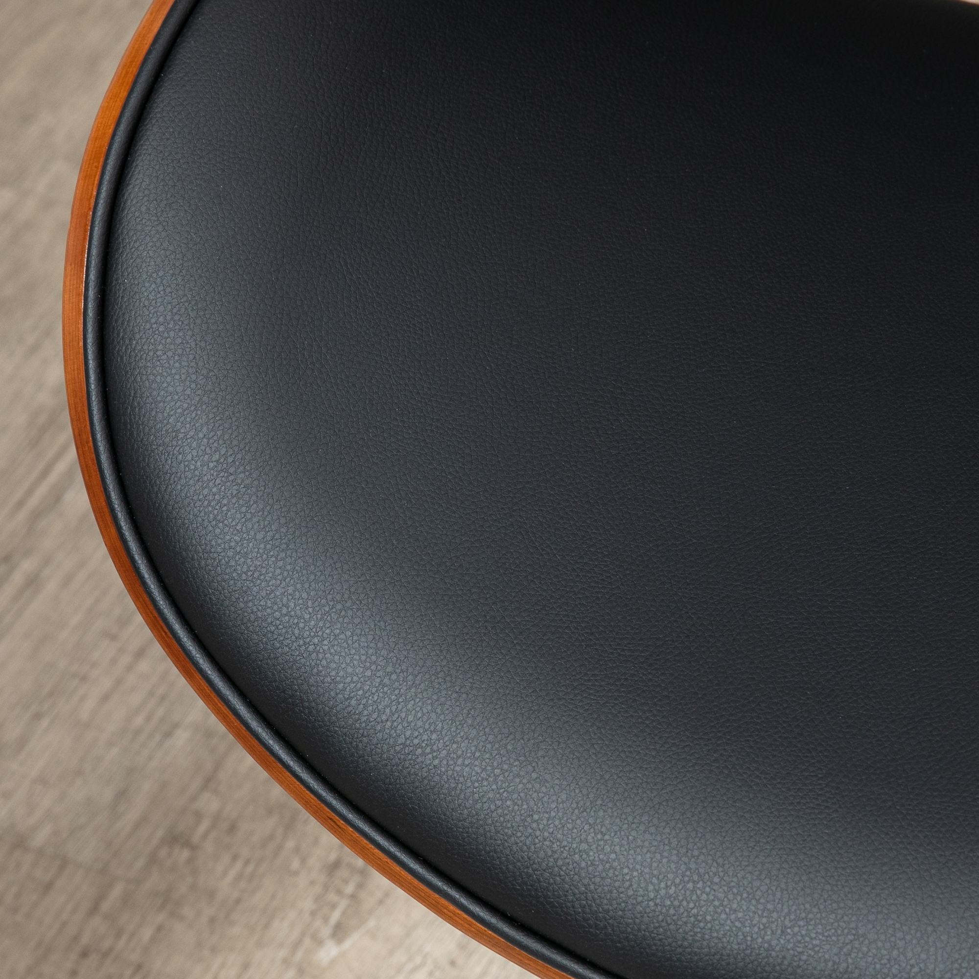 Primer plano de un asiento de cuero negro con marco de madera sobre suelo claro.