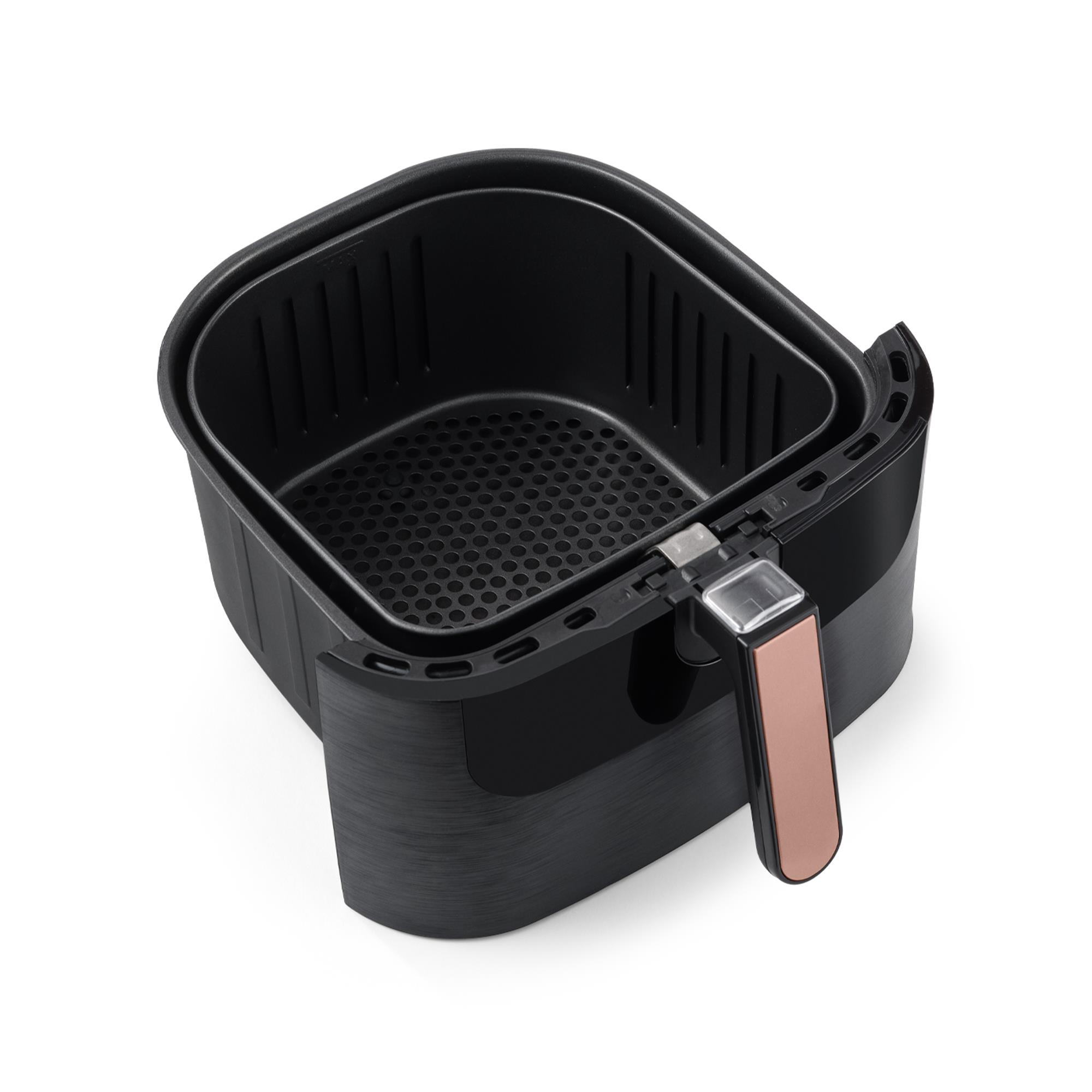 Beyaz arka planda bakır renkli sapı olan siyah bir airfryer sepeti.