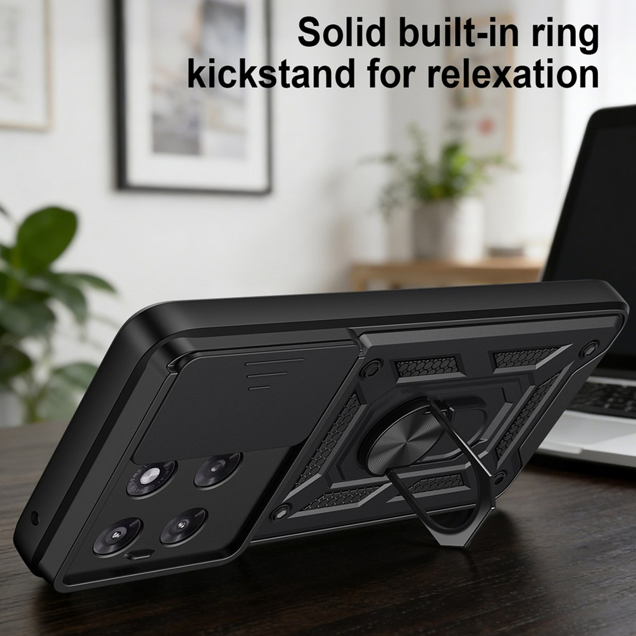 Zwarte telefoonhoes met geïntegreerde ringstandaard op een houten bureau.